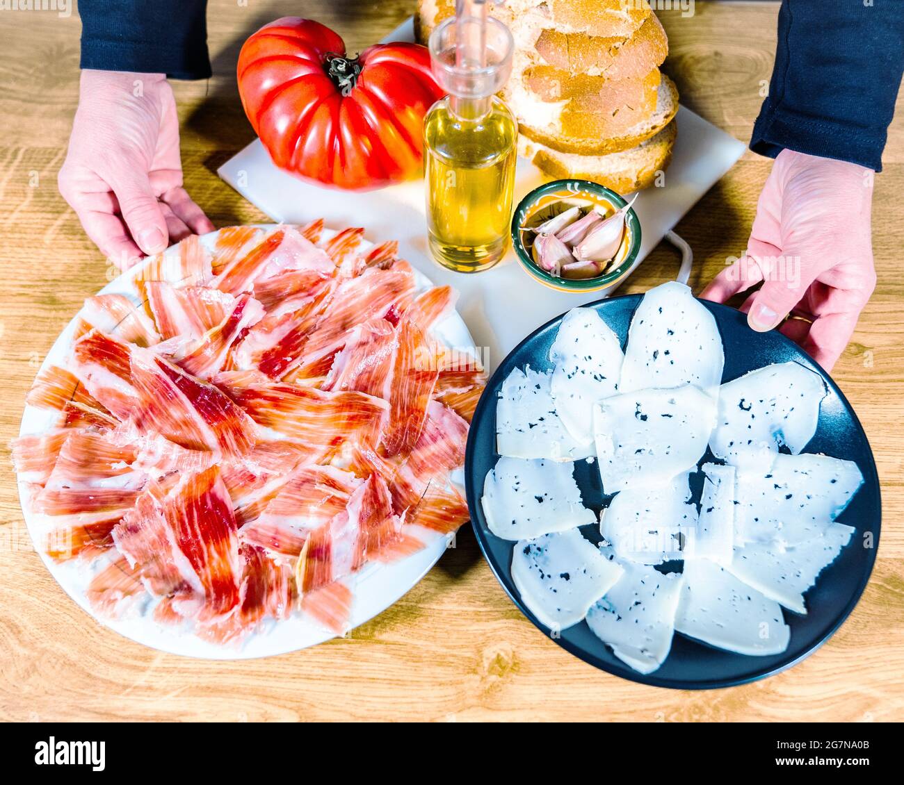 Assiette de jambon ibérique et fromage de chèvre servie dans deux assiettes  sur fond de bois. Cuisine typiquement espagnole ou catalane : jambon de  serrano, pain au fromage avec toma Photo Stock -