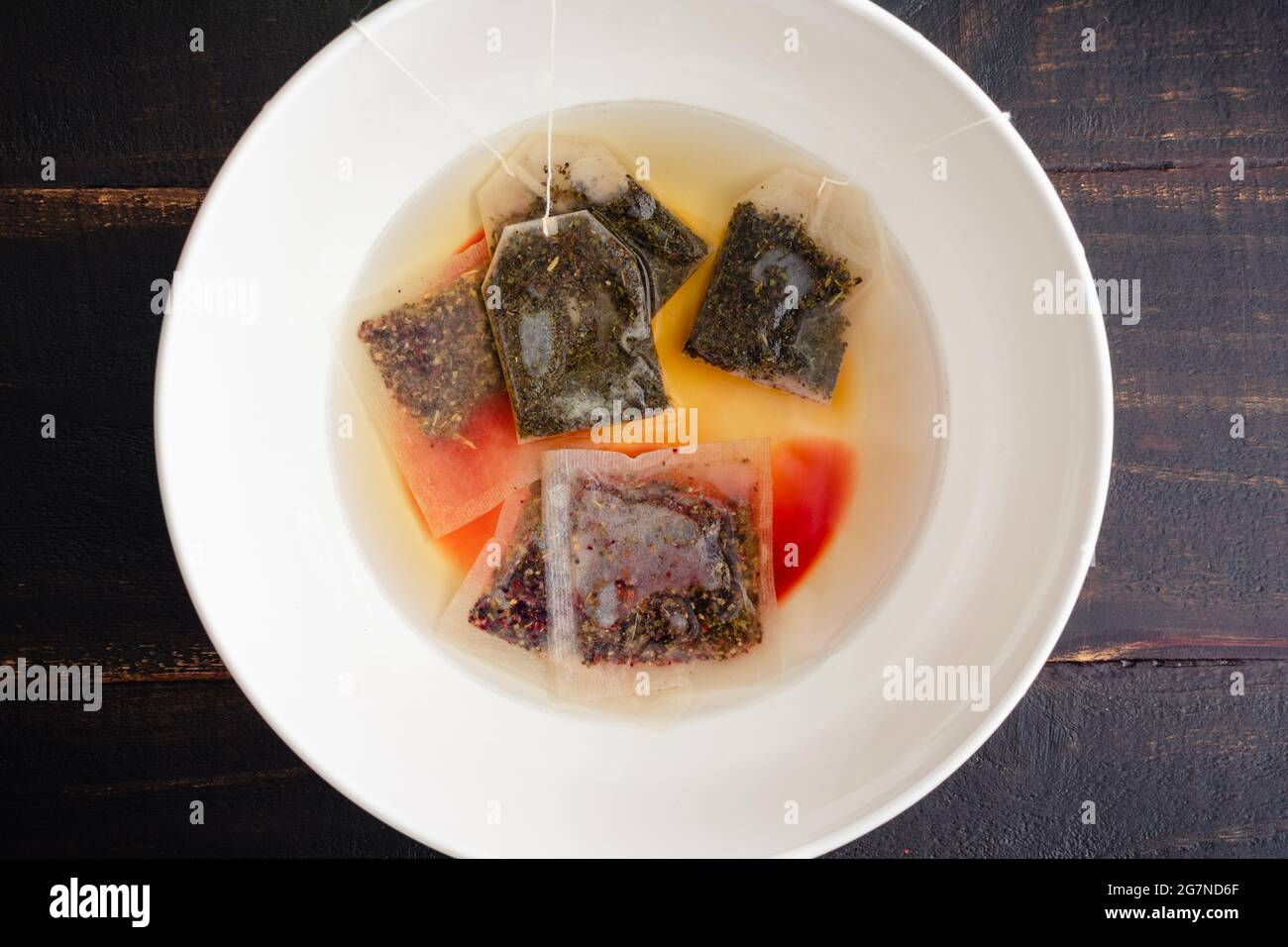 Sachets de thé à base d'herbes steeping dans un bol blanc : sachets de thé à base de framboises et de menthe poivrée, steeping dans un bol en céramique blanc Banque D'Images