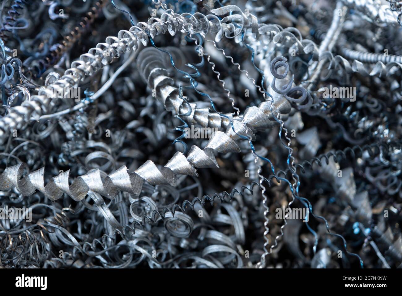 Recyclage des déchets d'acier. Aluminium, déchets de copeaux de fer après l'usinage de pièces métalliques sur un tour cnc. Gros plan de copeaux d'acier torsadés abstraits en spirale. Banque D'Images