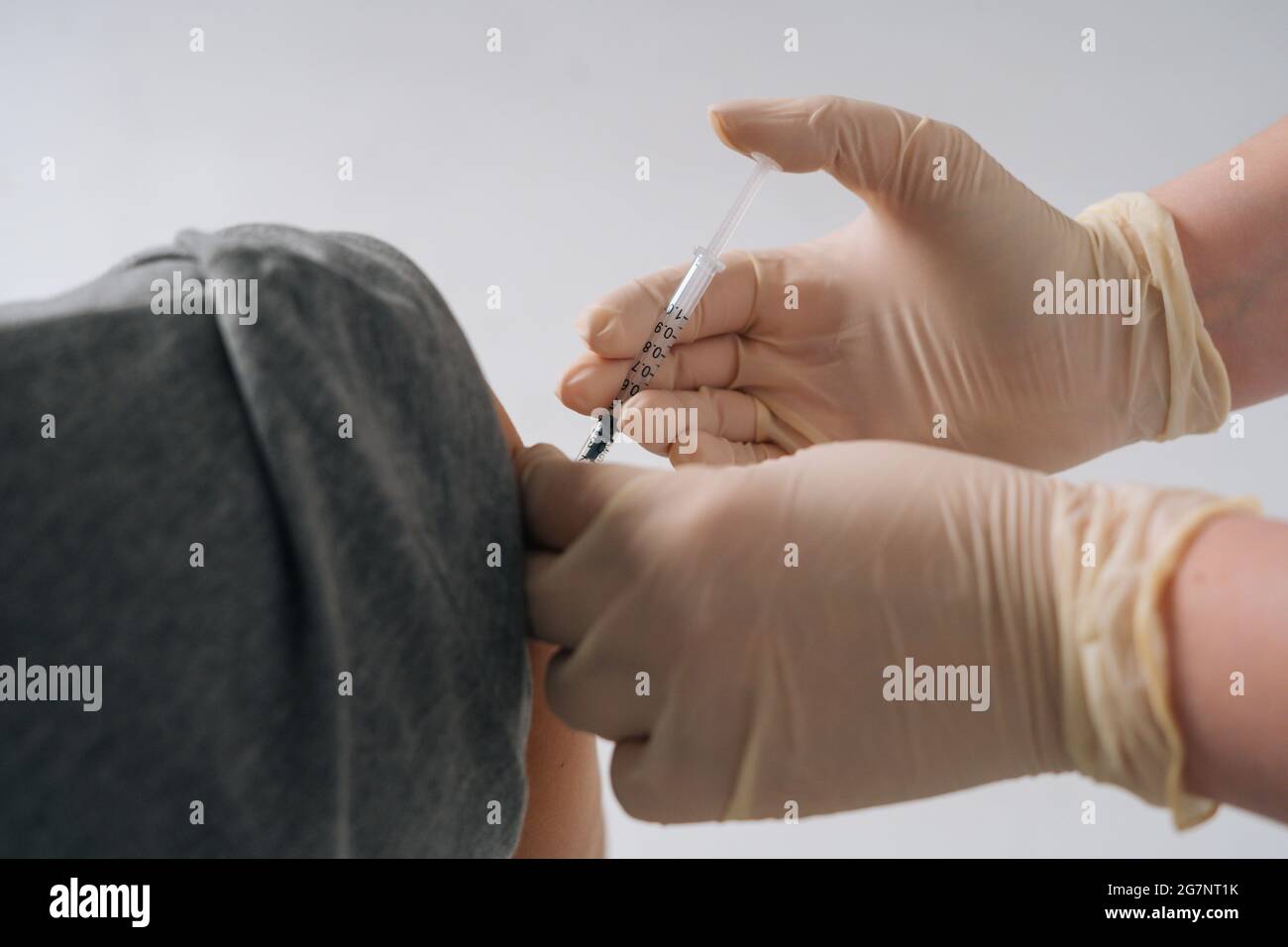 Gros plan de la femme médecin en sécurité gants médicaux donnant la dose de vaccin par injection à l'épaule sur fond blanc isolé. Banque D'Images
