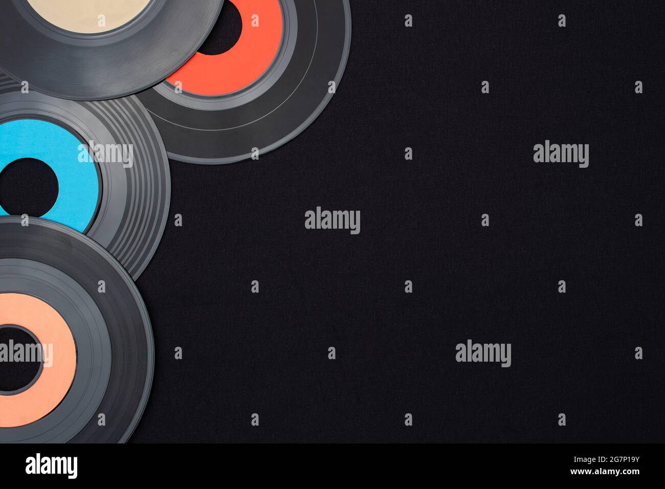 Un seul vinyle multicolore de 7 pouces sur fond noir placé dans le coin supérieur gauche avec un espace vide pour le texte. Plan d'étapage avec vue de dessus en bas. Rétro Banque D'Images