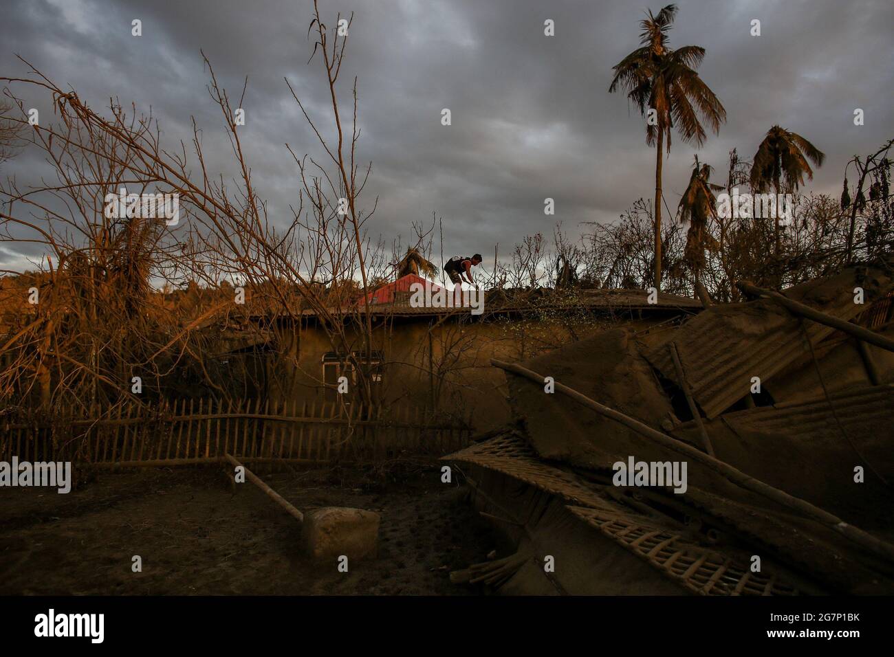 Un homme nettoie sa maison qui est couverte de cendres volcaniques après l'éruption du volcan Taal dans la province de Batangas au sud de Manille, Philippines. Le volcan Taal est une grande caldeira remplie par le lac Taal aux Philippines. Situé dans la province de Batangas, le volcan est l'un des volcans les plus actifs du pays, avec 34 éruptions historiques enregistrées, toutes concentrées sur l'île Volcano, près du milieu du lac Taal. La dernière éruption a eu lieu le 12 janvier 2020. Philippines. Banque D'Images