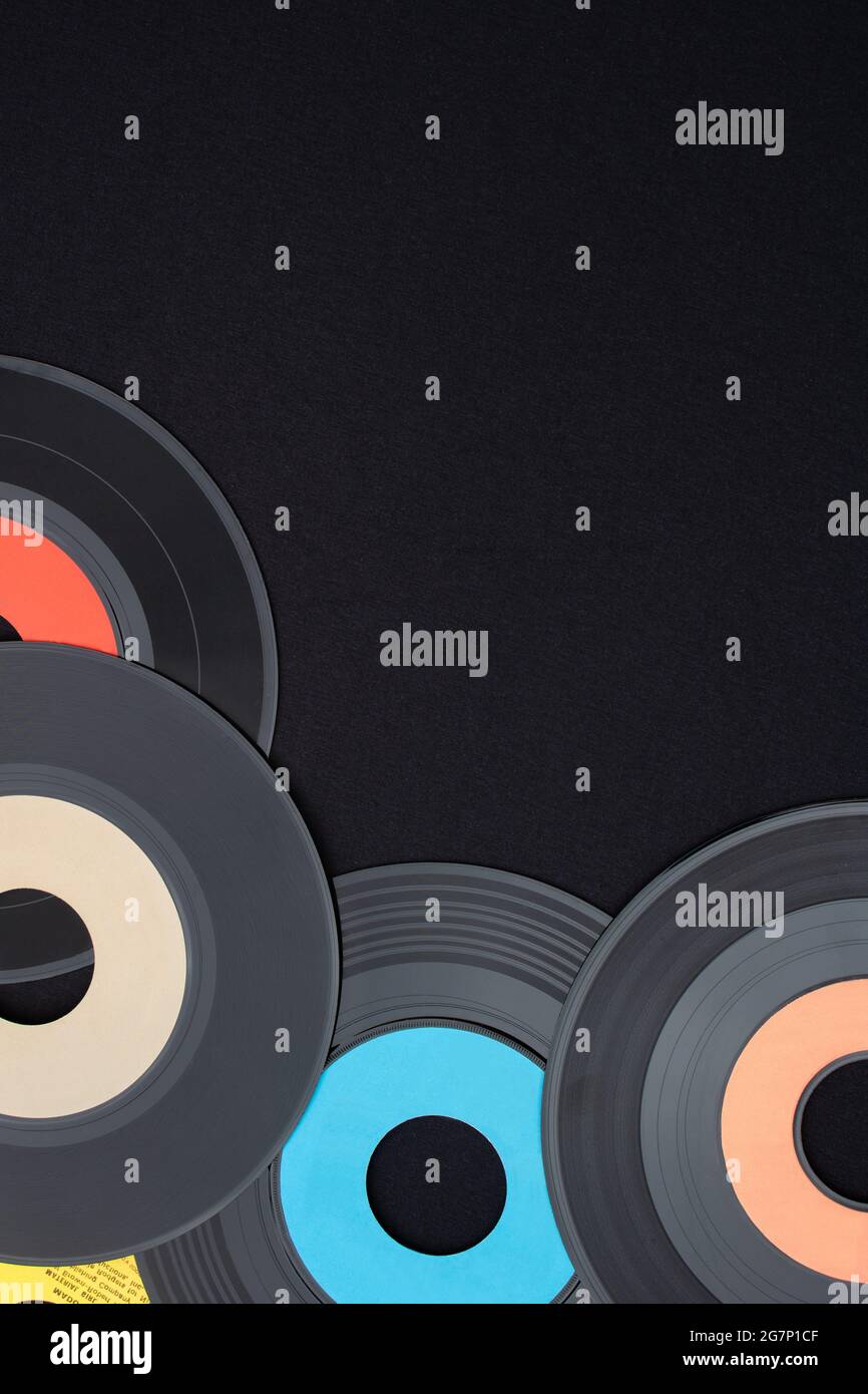 Vinyle simple multicolore de 7 pouces sur fond noir placé dans le coin inférieur gauche avec un espace vide pour le texte. Plan d'étapage avec vue de dessus en bas. Rétro Banque D'Images