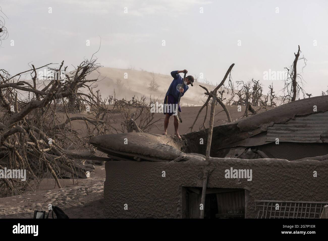 Un homme nettoie sa maison qui est couverte de cendres volcaniques après l'éruption du volcan Taal dans la province de Batangas au sud de Manille, Philippines. Le volcan Taal est une grande caldeira remplie par le lac Taal aux Philippines. Situé dans la province de Batangas, le volcan est l'un des volcans les plus actifs du pays, avec 34 éruptions historiques enregistrées, toutes concentrées sur l'île Volcano, près du milieu du lac Taal. La dernière éruption a eu lieu le 12 janvier 2020. Philippines. Banque D'Images