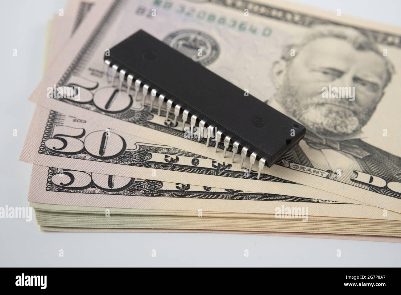 Grande puce électronique placée au-dessus de la pile de 50 billets de banque en dollars américains. Concept d'investissement dans l'industrie des semi-conducteurs et la pénurie de puces d'or. Banque D'Images