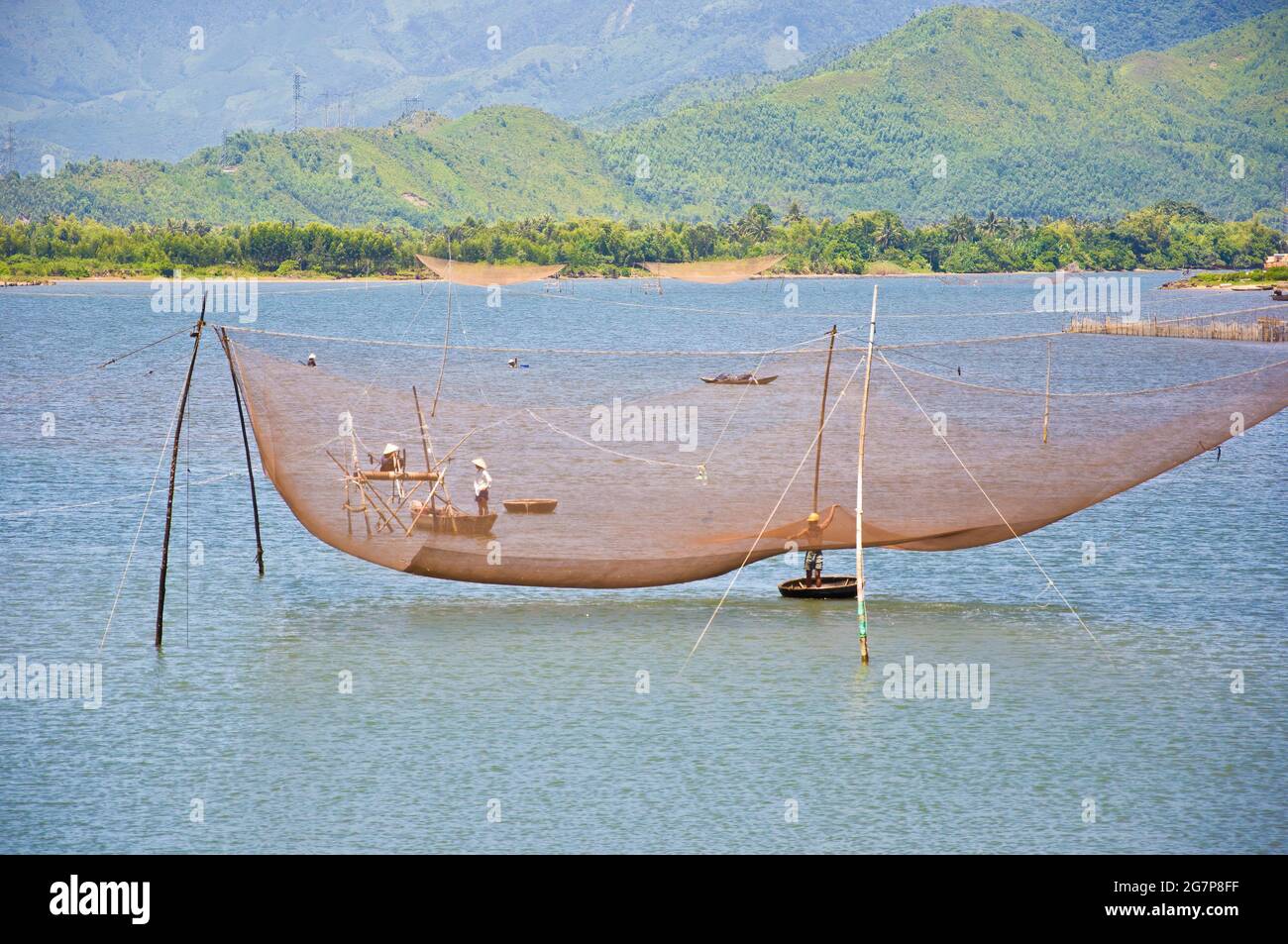 Grand filet de pêche dans l'eau, avec des pêcheurs locaux dans des petits bateaux faits de l'homme, Vietnam. Banque D'Images
