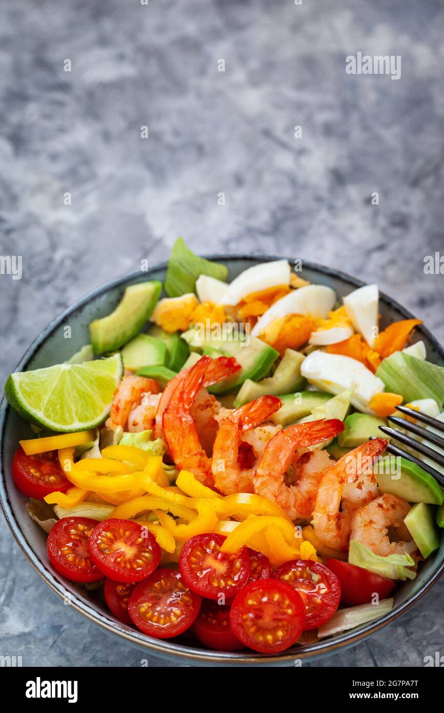 Salade fraîche délicieuse aux crevettes, à l'avocat, aux œufs, au poivron, aux tomates et aux herbes Banque D'Images