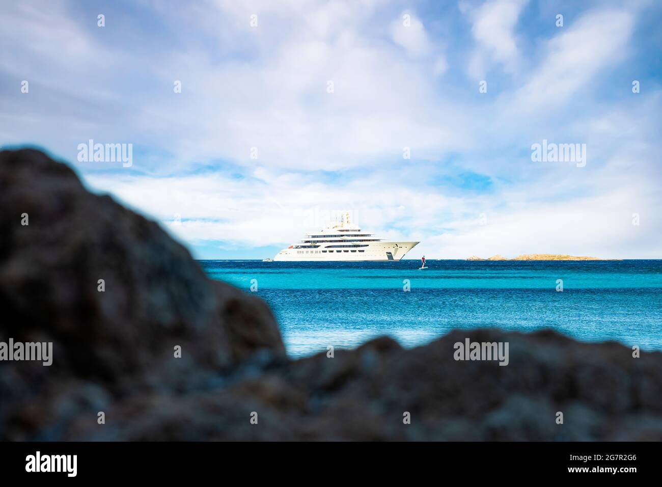 (Mise au point sélective) vue imprenable sur un yacht de luxe naviguant sur une eau turquoise tandis qu'un touriste défoqué est sur un hydroptère électrique. Banque D'Images