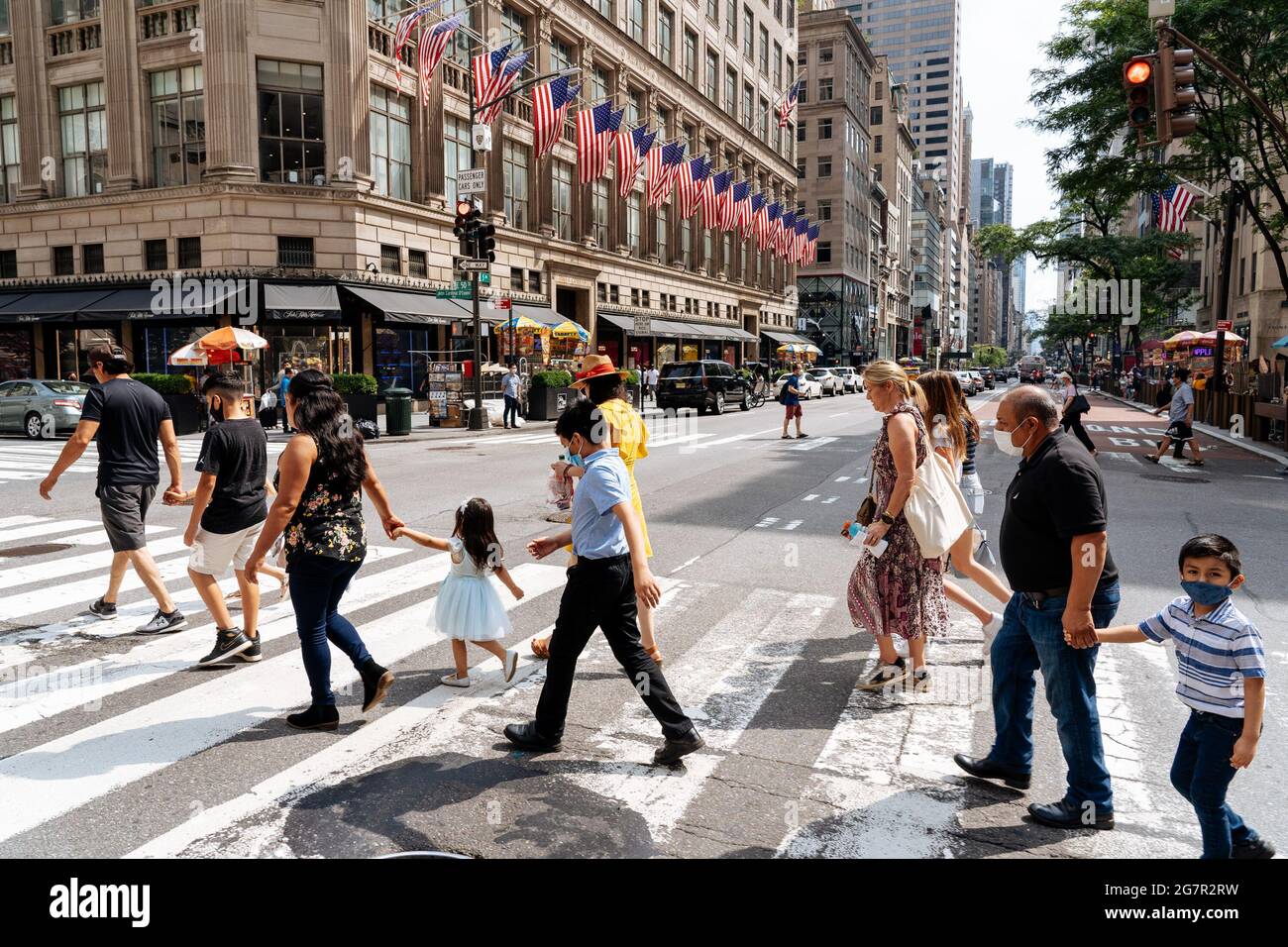 New York, États-Unis. 11 juillet 2021. Les passants traversent la 5e Avenue  en face de la Saks Fifth Avenue, dans un passage en croix. New York est sur  le point de se
