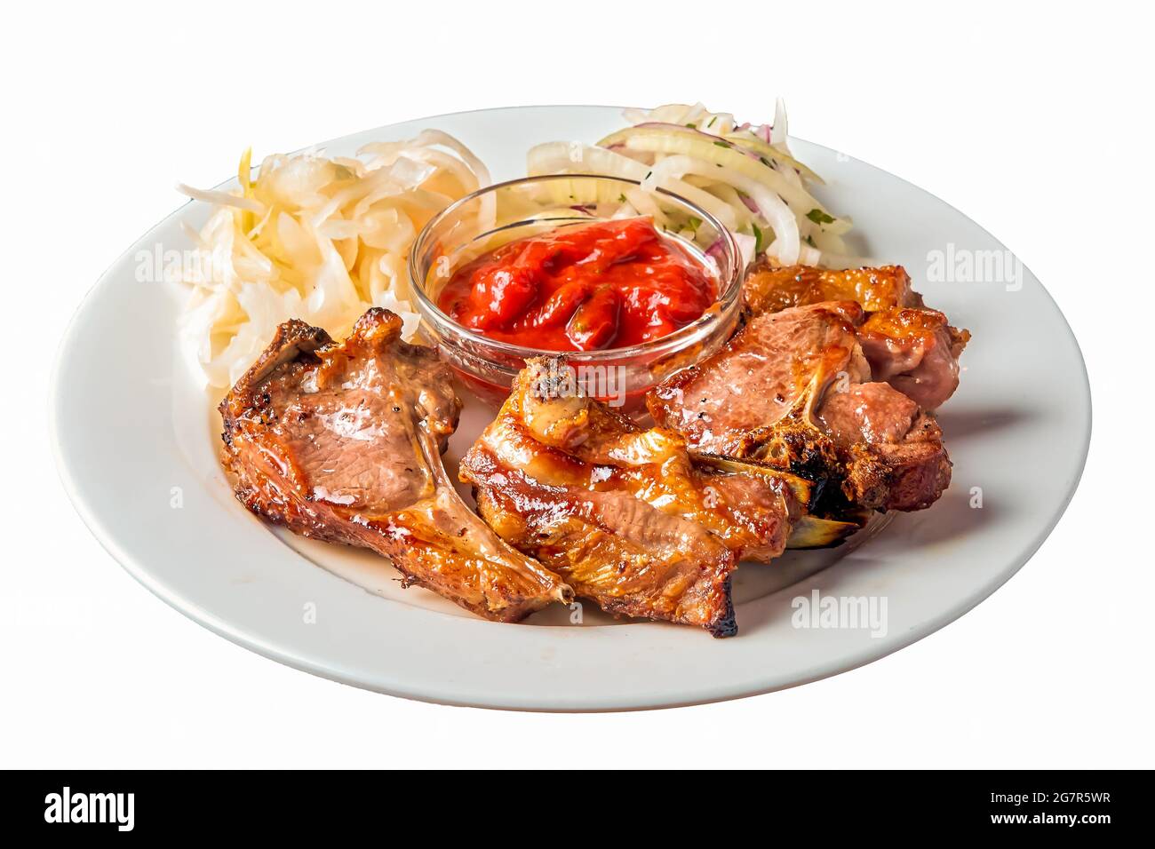 un kebab d'agneau sur un os repose sur une assiette sur un fond blanc isolé Banque D'Images
