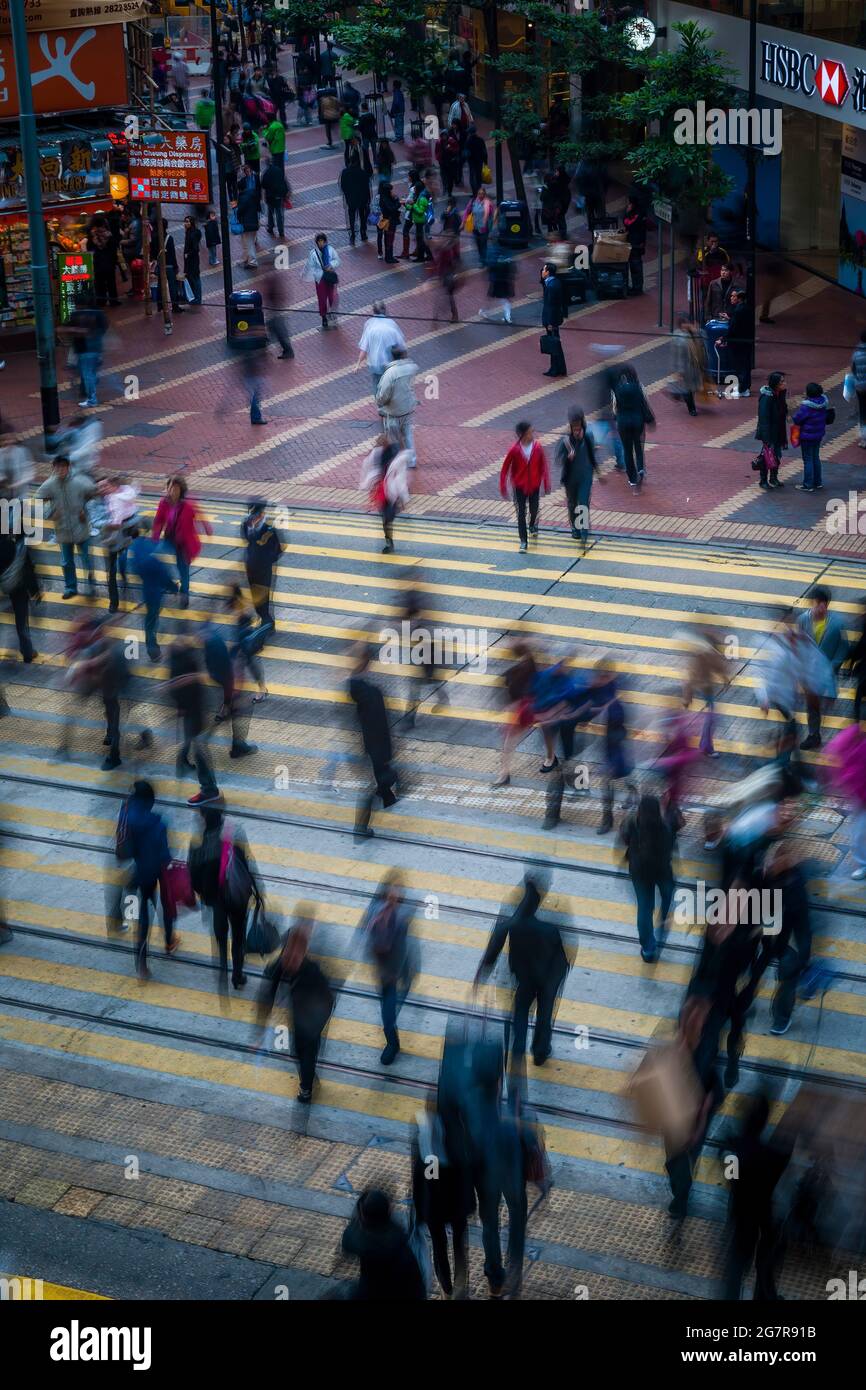 Les piétons traversent les voies de tramway de Causeway Bay, sur l'île de Hong Kong, avec un effet de flou dû à une vitesse d'obturation lente Banque D'Images