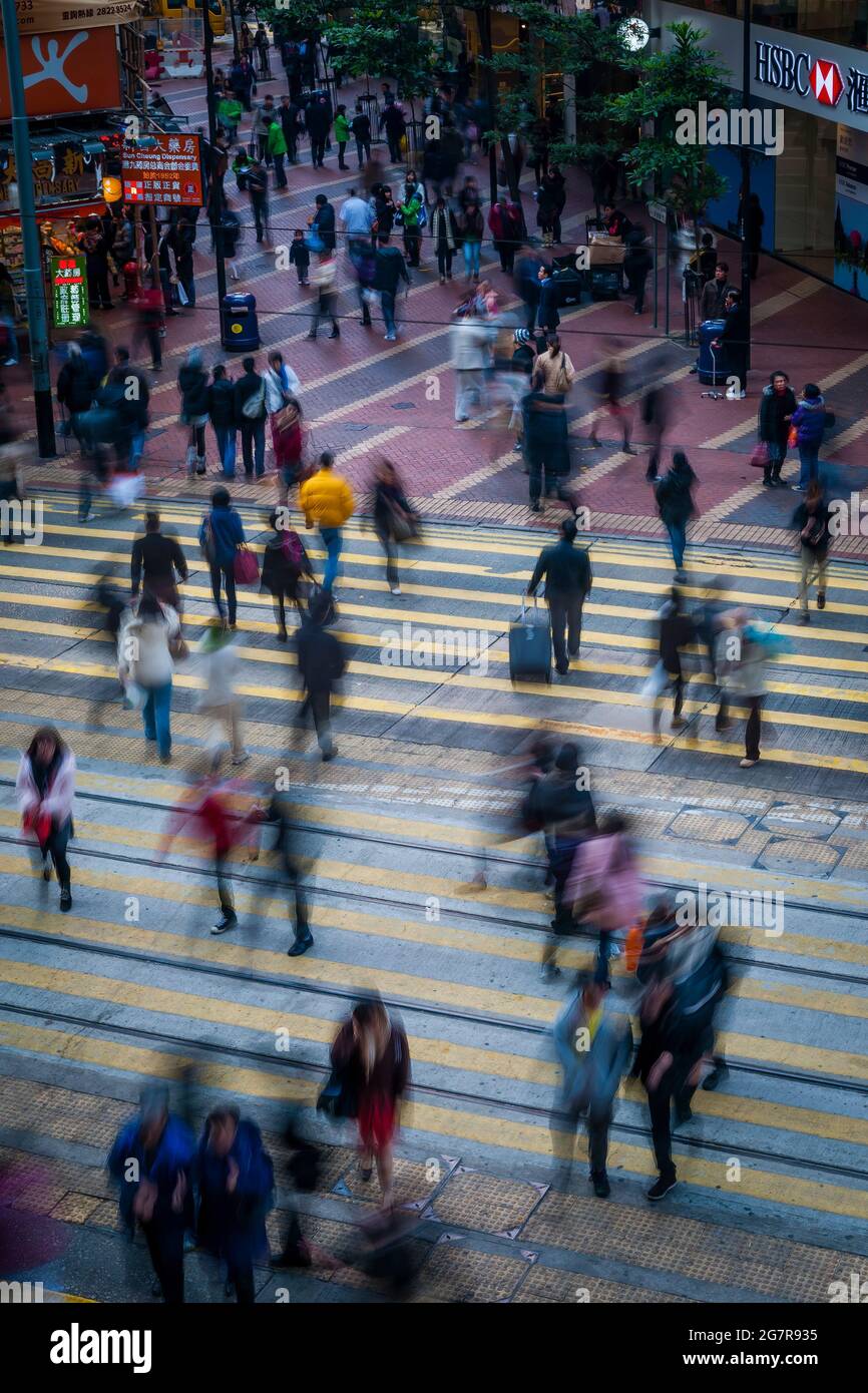Les piétons traversent les voies de tramway de Causeway Bay, sur l'île de Hong Kong, avec un effet de flou dû à une vitesse d'obturation lente Banque D'Images