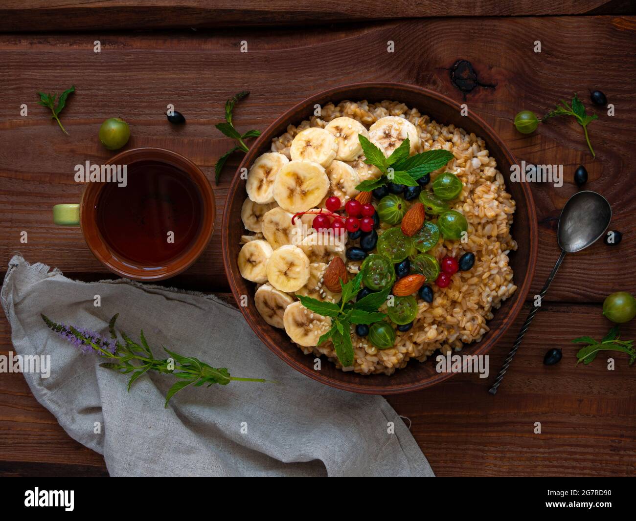 Bol de porridge à flocons d'avoine avec baies fraîches, fruits, noix, feuilles de menthe tasse à thé. Nourriture saine repas d'avoine matin petit déjeuner vue de dessus. Grain entier c Banque D'Images