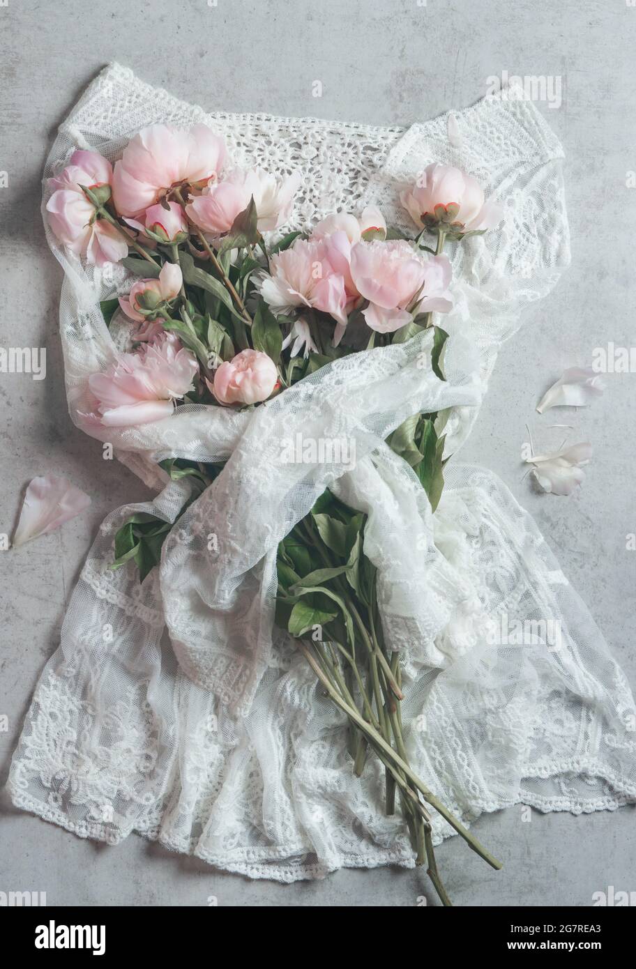 Belle dentelle blanche mini robe hugs bouquet de roses pâles pivoines fleurs. Vue de dessus Banque D'Images