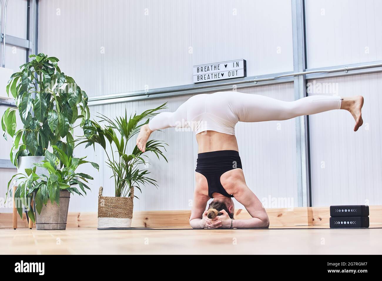 Femme russe caucasienne faisant une pose de yoga avancée dans un studio Banque D'Images