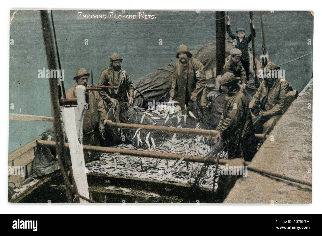 Carte postale teintée originale du début des années 1900 de pêcheurs vidant des pilchards (sardines) des filets, (peut-être filets de seine) série d'Argall, vers 1910 - Cornouailles. Banque D'Images