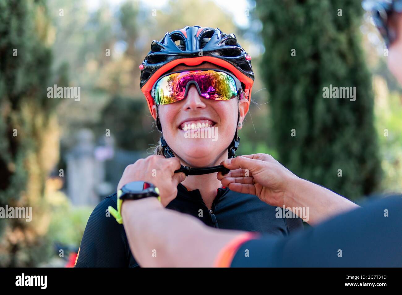 Homme blanc méconnaissable fixant le casque de vélo d'un jeune cycliste caucasien Banque D'Images