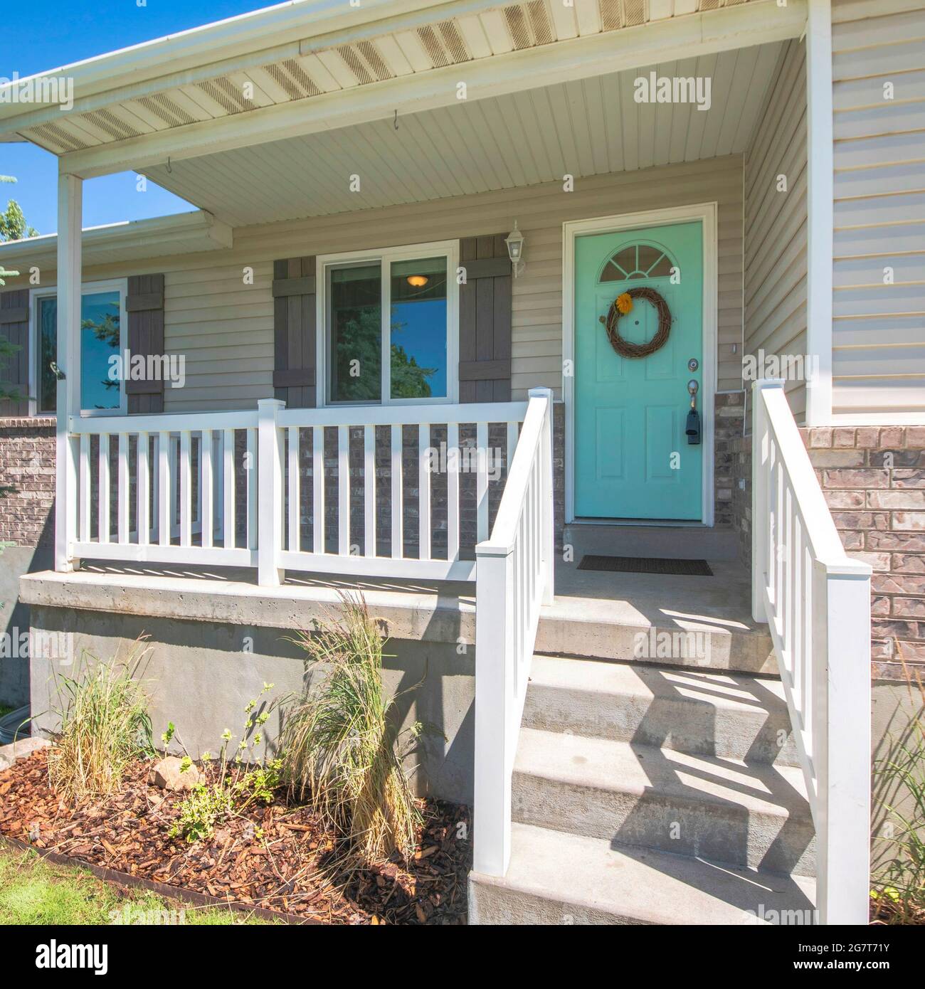 Cadre carré extérieur d'une maison avec briques, porche surélevé et fenêtres à double vitrage Banque D'Images