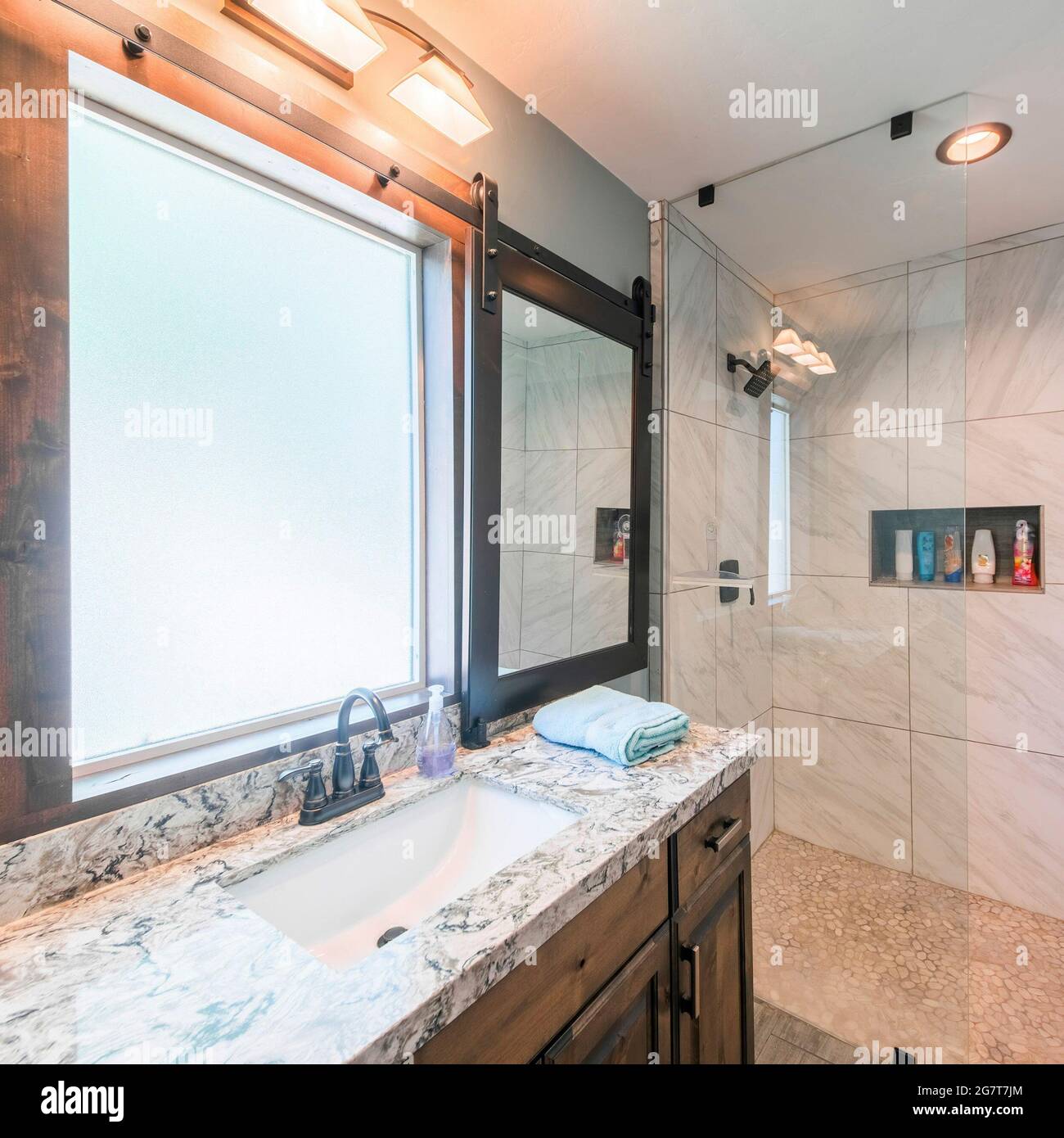 Cadre carré intérieur de la salle de bains avec murs carrelés, lumières  chaudes et panneau de fenêtre coulissant avec miroir Photo Stock - Alamy
