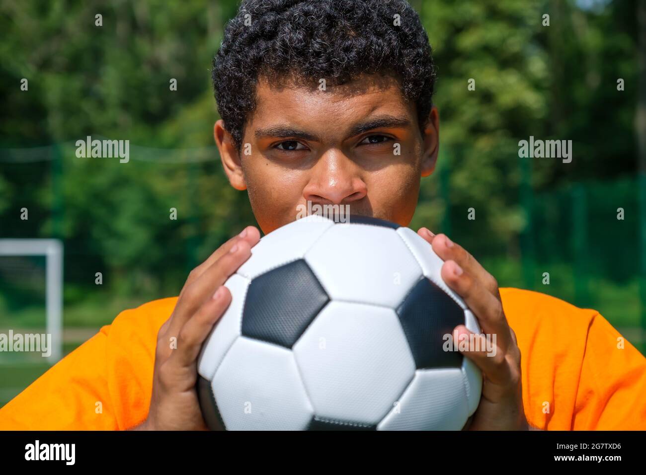 L'homme brésilien tient le ballon de football de près tout en se tenant sur le terrain de sport Banque D'Images