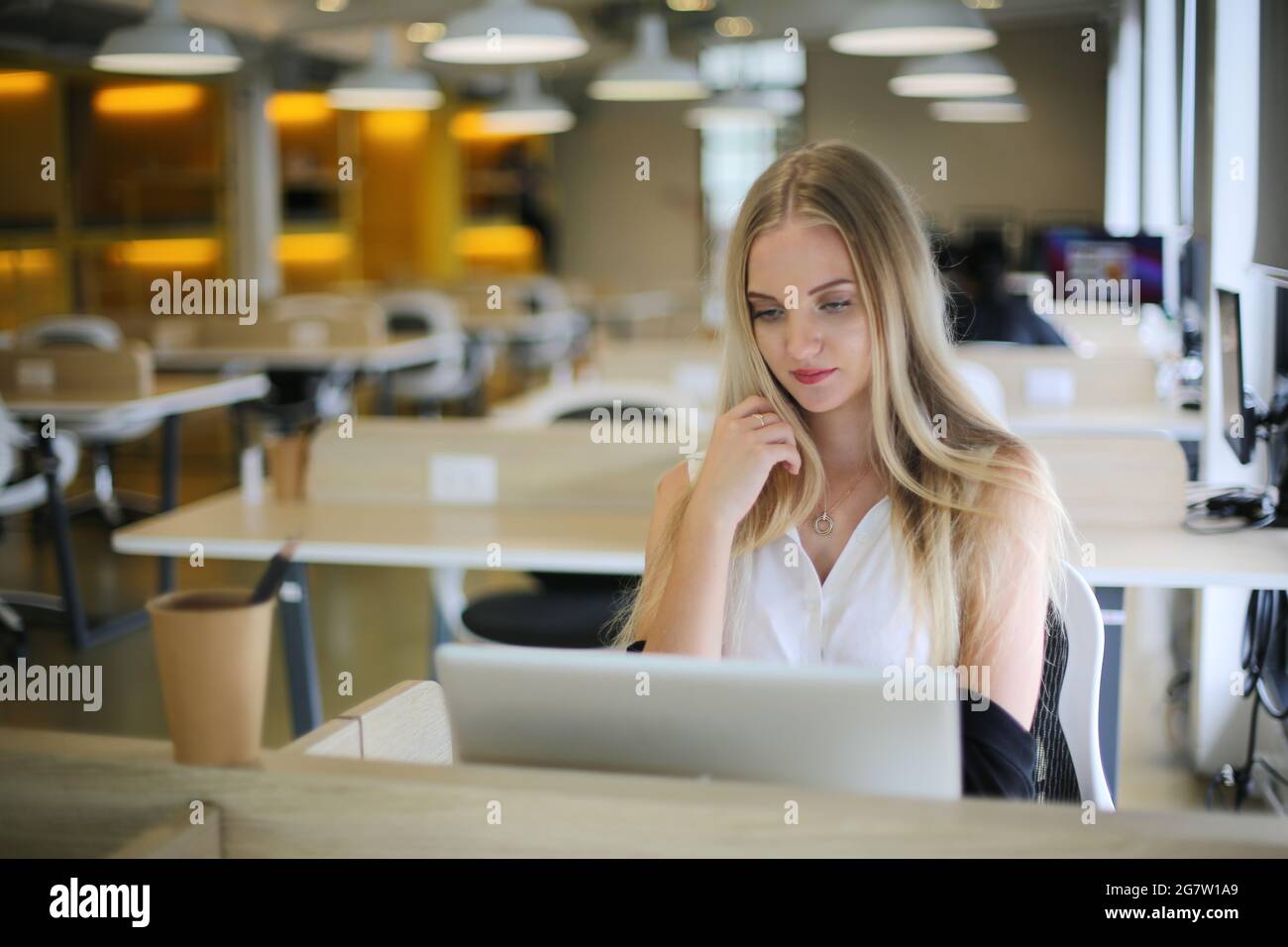 Belle jeune femme travaillant avec un ordinateur portable concentré et souriant Banque D'Images