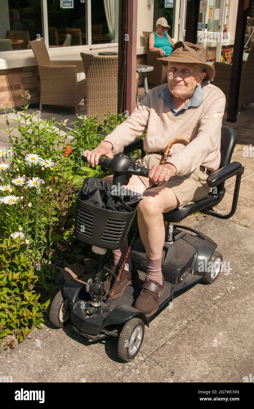 Vieil homme sur le scooter de la chaussée Banque D'Images