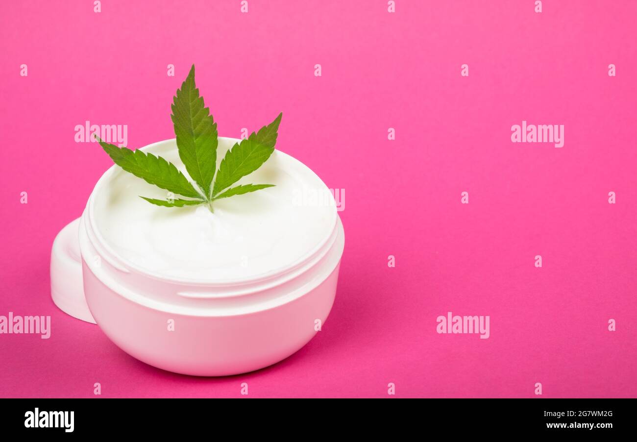 crème cosmétique de soin de la peau avec extrait de chanvre sur fond rose copie espace. Banque D'Images