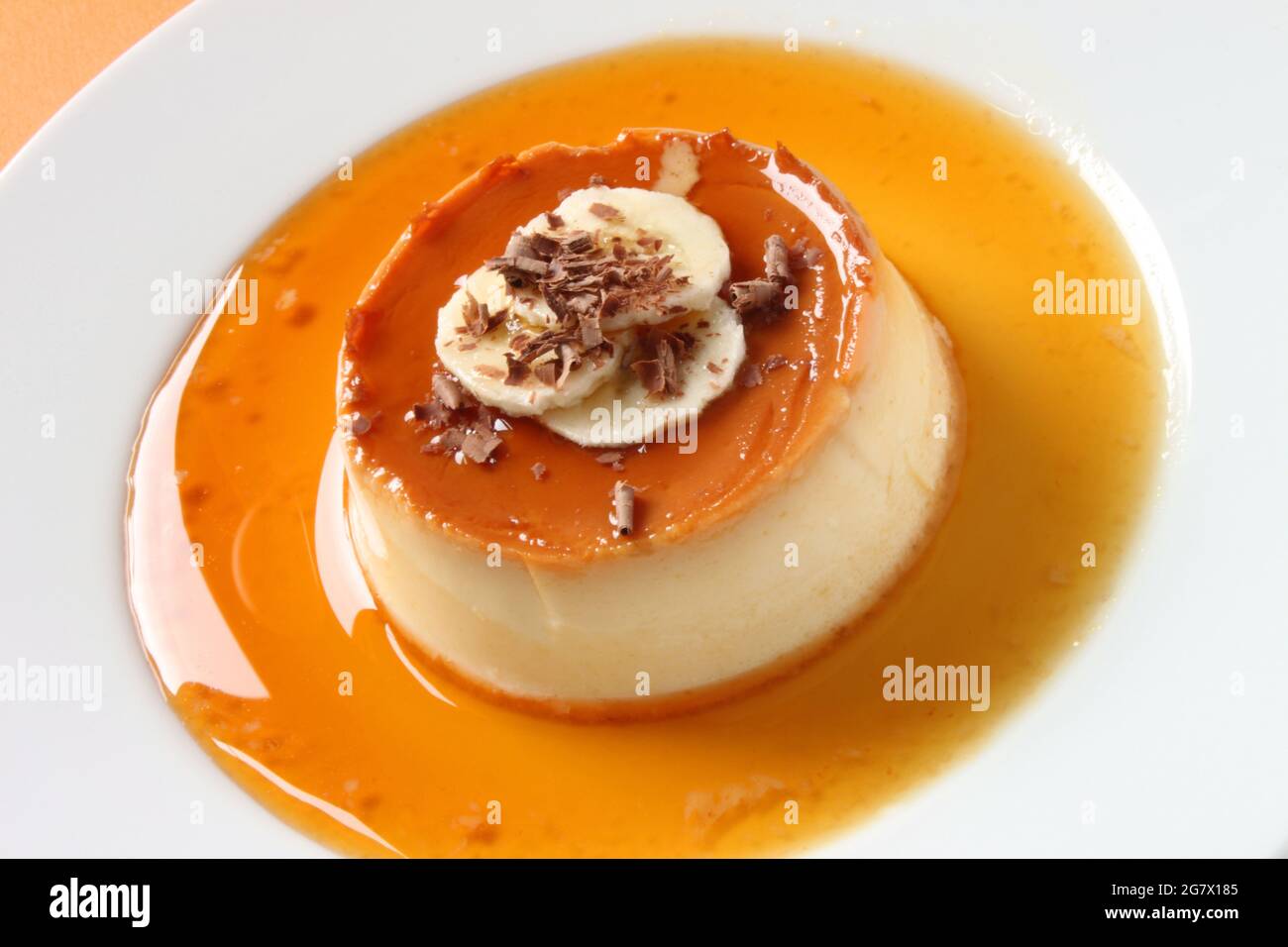 Une crème caramel décorée de tranches de banane et de copeaux de chocolat. Banque D'Images