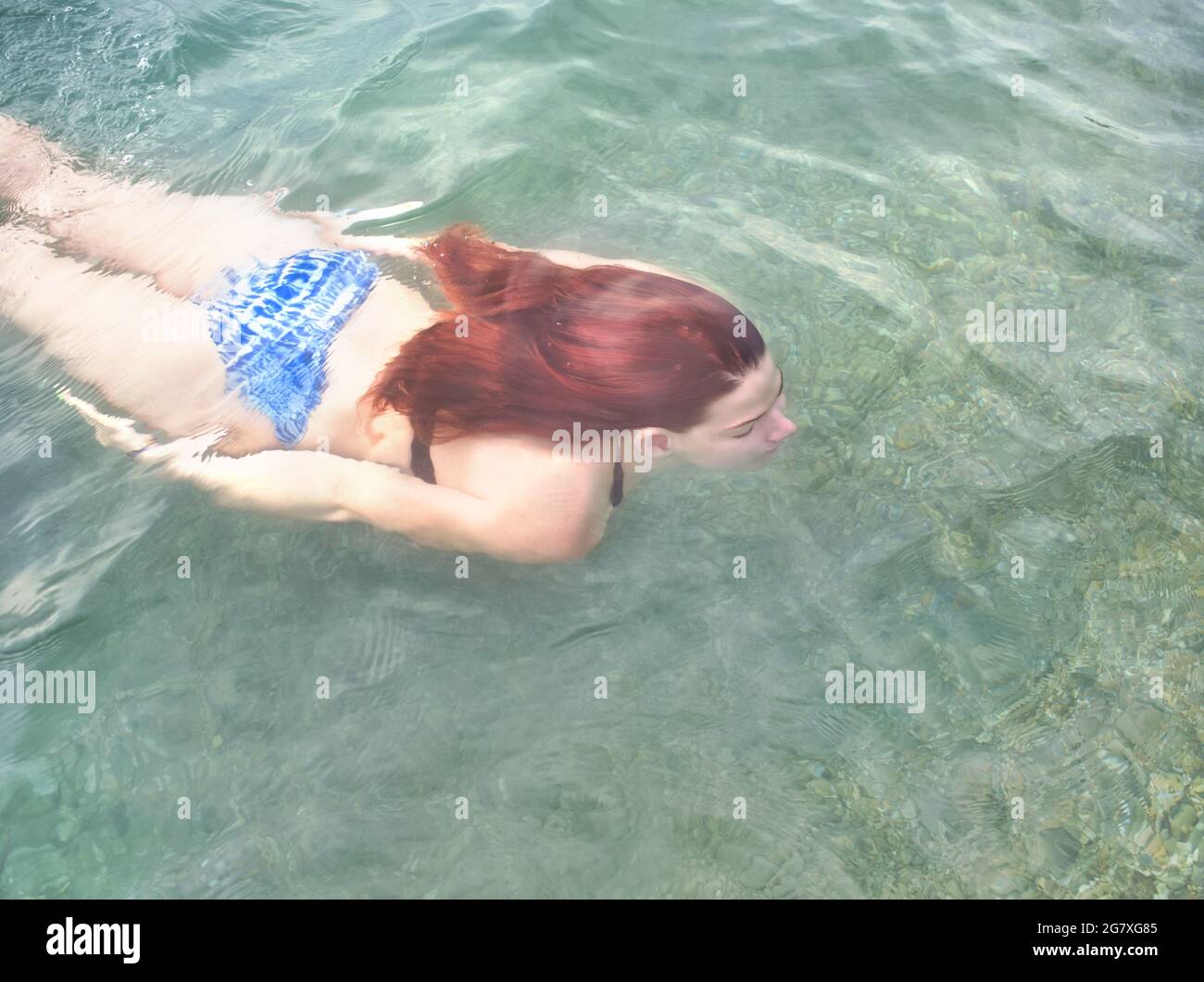 Jeune femme aux cheveux rouges natation sous l'eau Banque D'Images