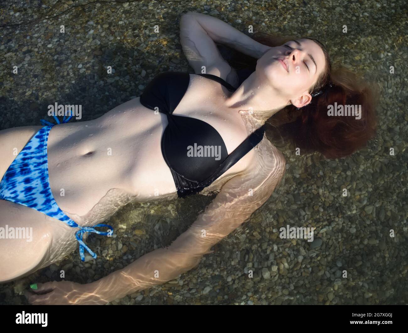 Jeune femme avec des cheveux rouges bains de soleil dans l'eau Banque D'Images