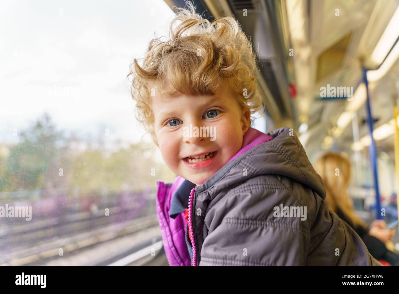 Un jeune enfant heureux voyageant en train de banlieue Banque D'Images