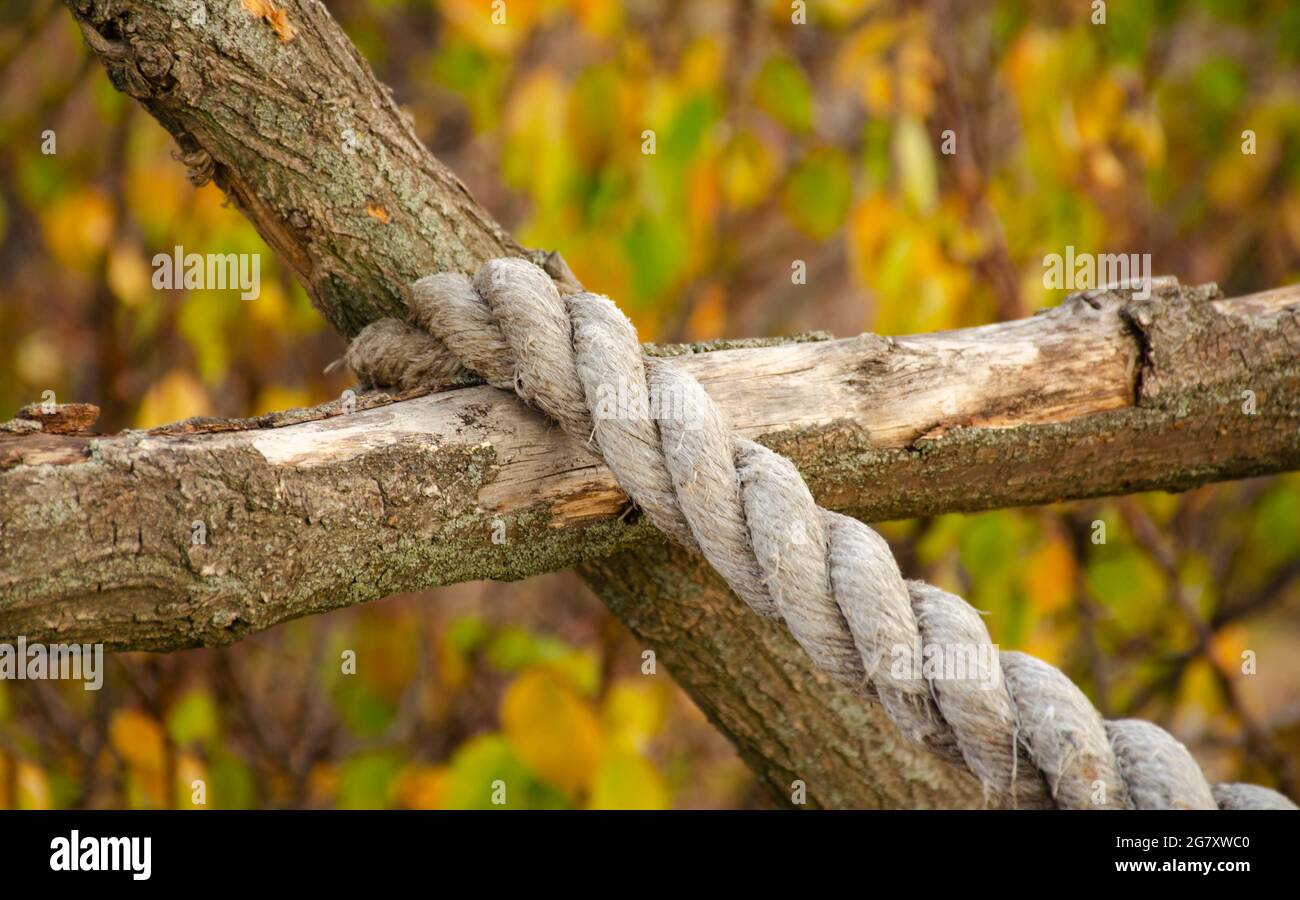 Corde rustique attachée en bois. Clôture de poteau en bois avec corde suspendue. La corde est suspendue sur une clôture en bois. Gros plan Banque D'Images