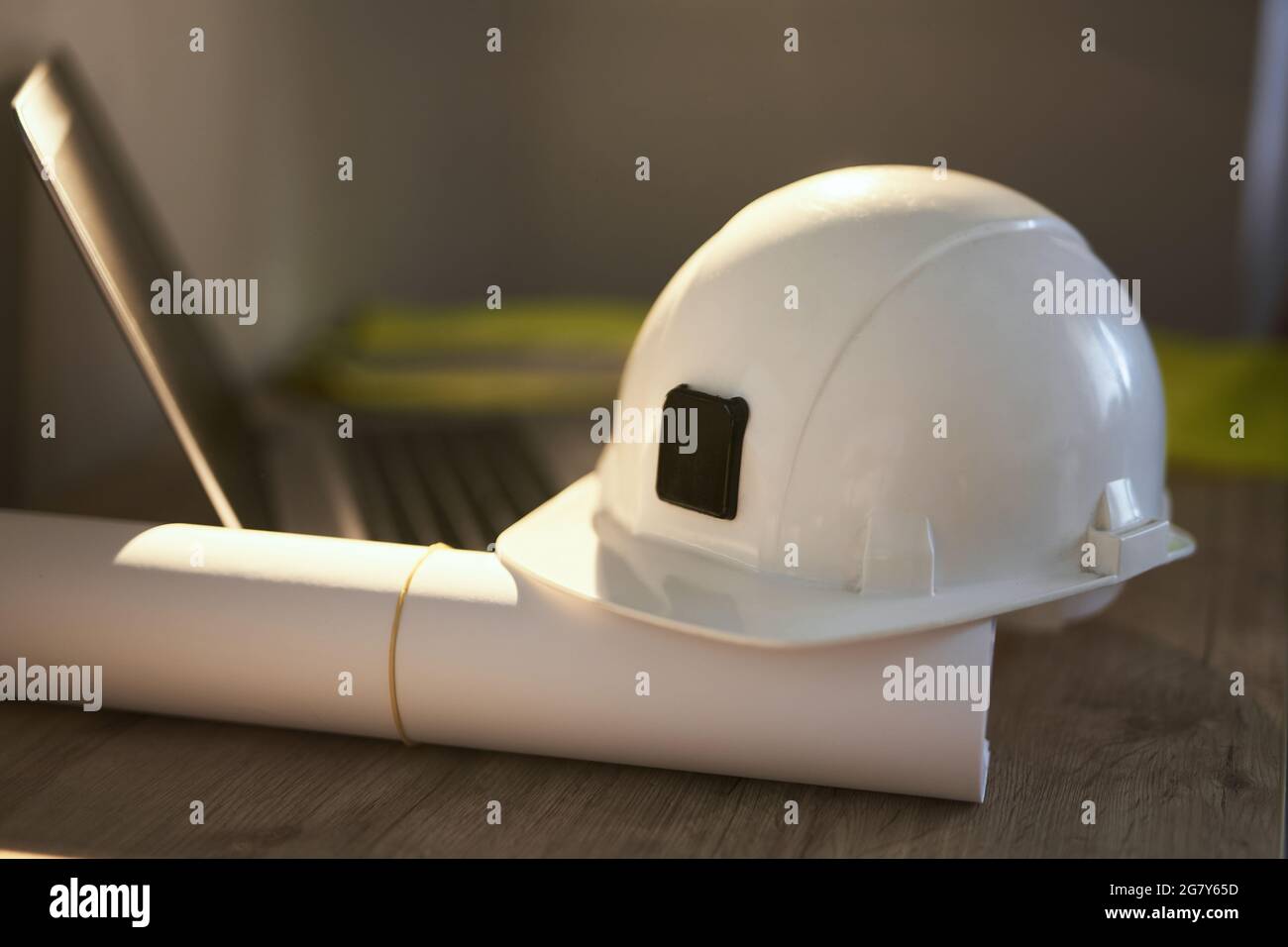 Concept de construction, de conception, d'architecture ou d'industrie du bâtiment. Casque de sécurité blanc, plans roulés et ordinateur portable sur la table de l'ingénieur. Photo de haute qualité Banque D'Images