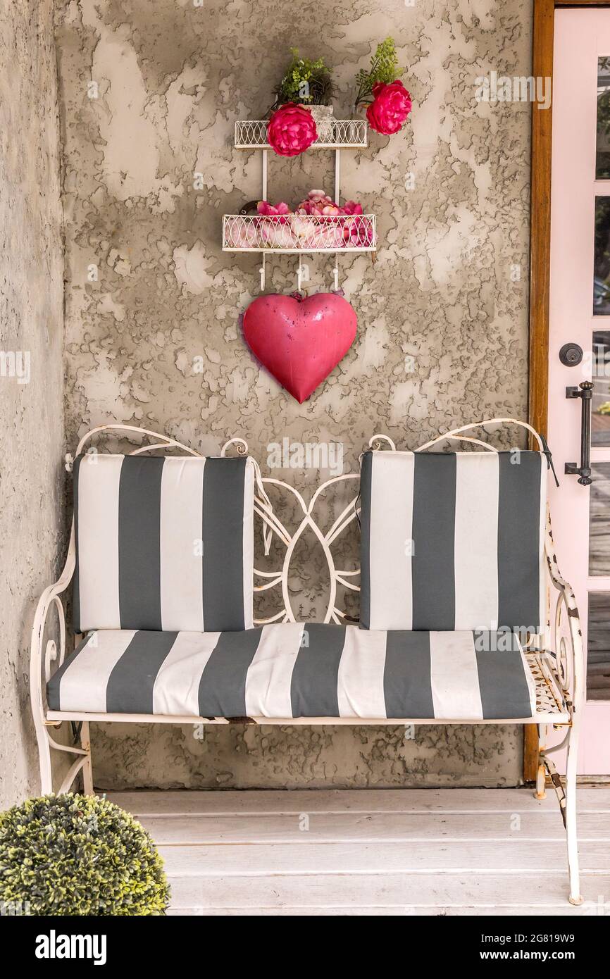 Un patio extérieur avec un canapé à rayures noires et blanches et un coeur rouge suspendu Banque D'Images