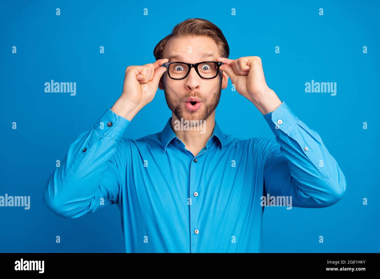 Photo du jeune homme excité heureux sourire positif stupéfié nouvelles surpris isolé sur fond bleu de couleur Banque D'Images