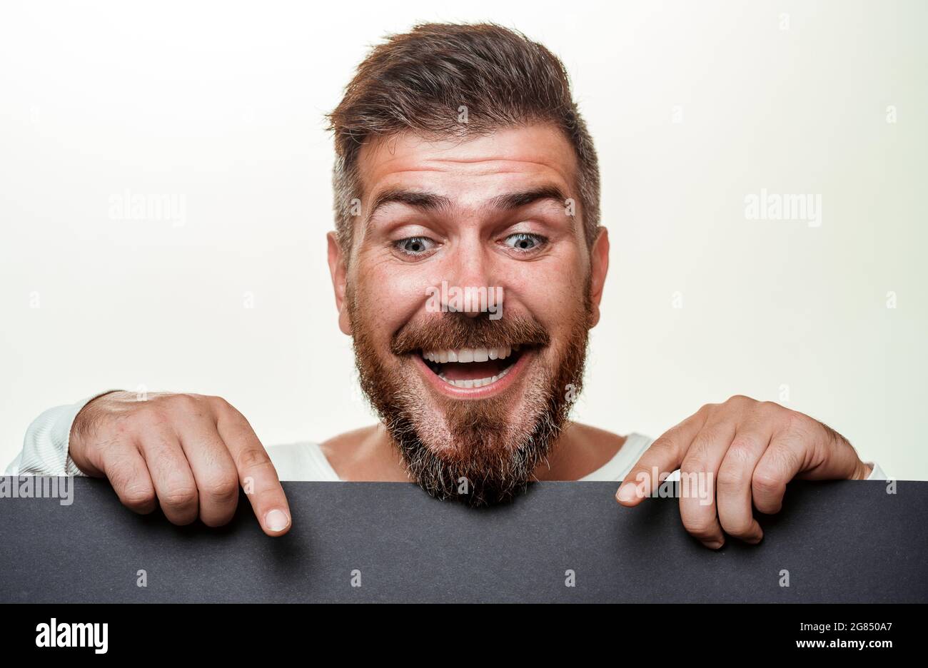 Homme barbu tient des bannières de solde de vendredi noires. Texte du Vendredi fou. Portrait en gros plan. Fond noir vendredi. Prêt pour le texte, le slogan ou le produit. Banque D'Images