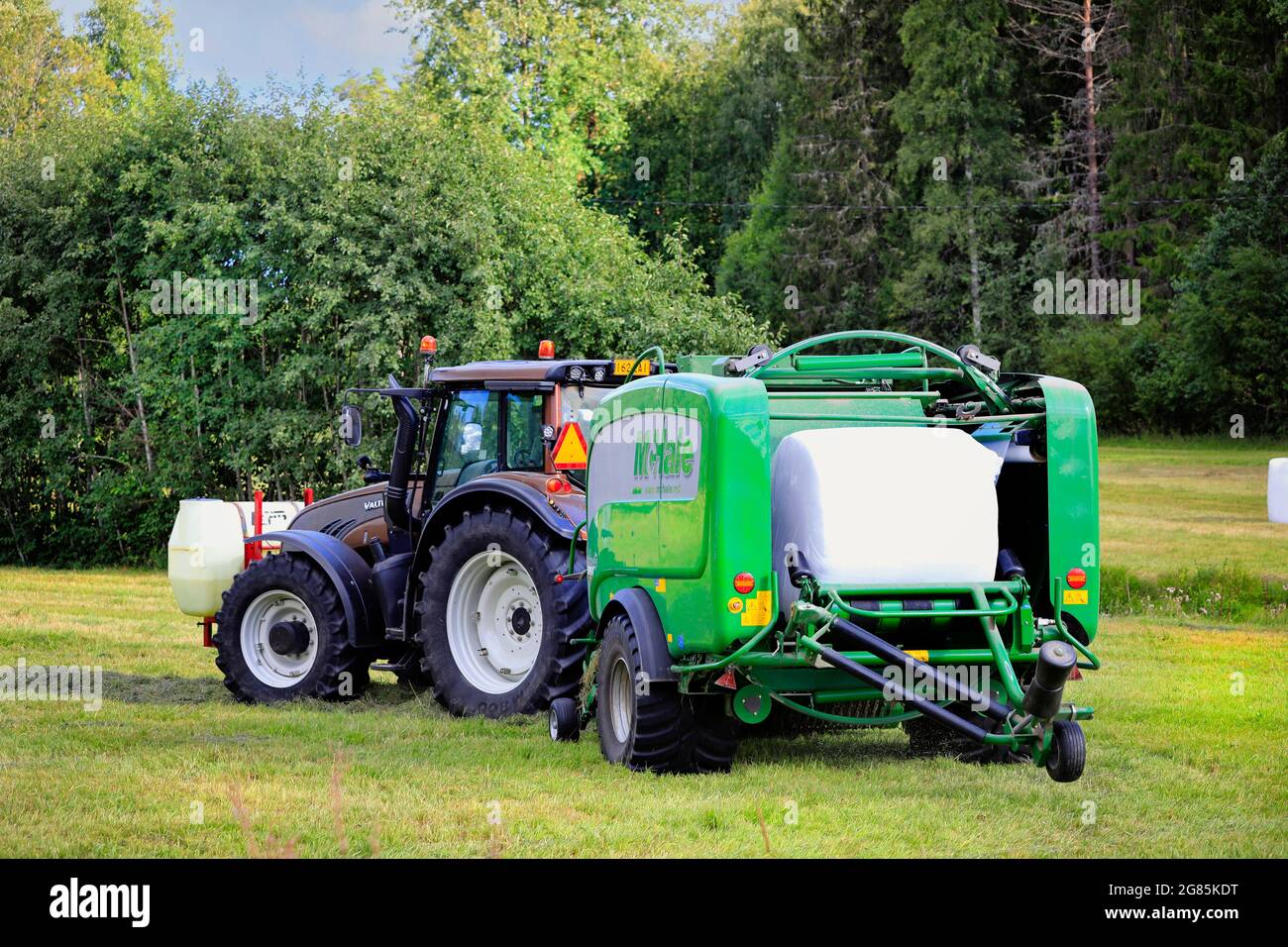 Agriculteur travaillant dans un champ de foin avec un tracteur Valtra et une enrubanneuse à ramasseuse-presse intégrée McHale 3 plus. Salo, Finlande. 28 août 2020. Banque D'Images