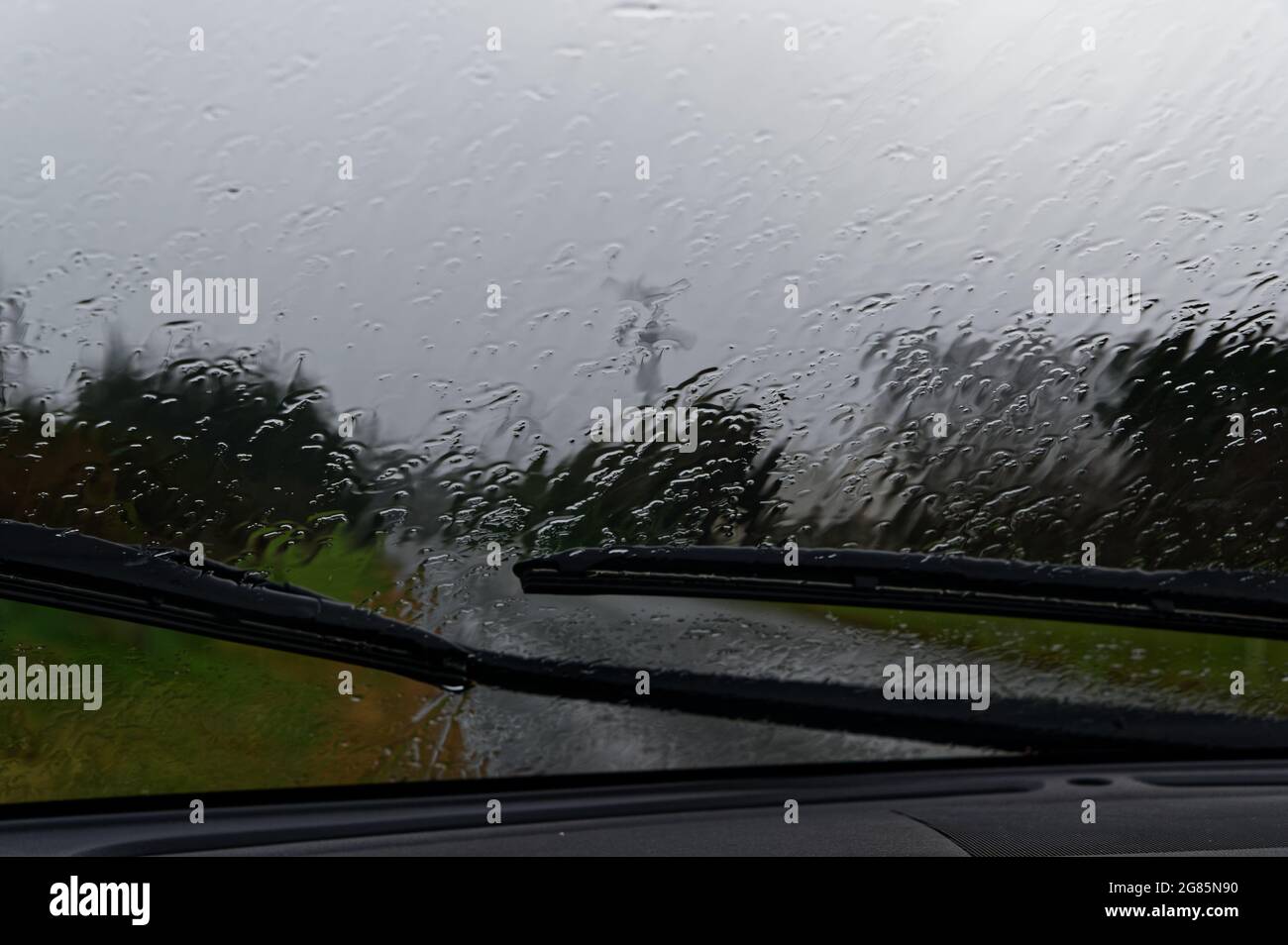 La pluie tombe sur le pare-brise d'une voiture par temps pluvieux Banque D'Images