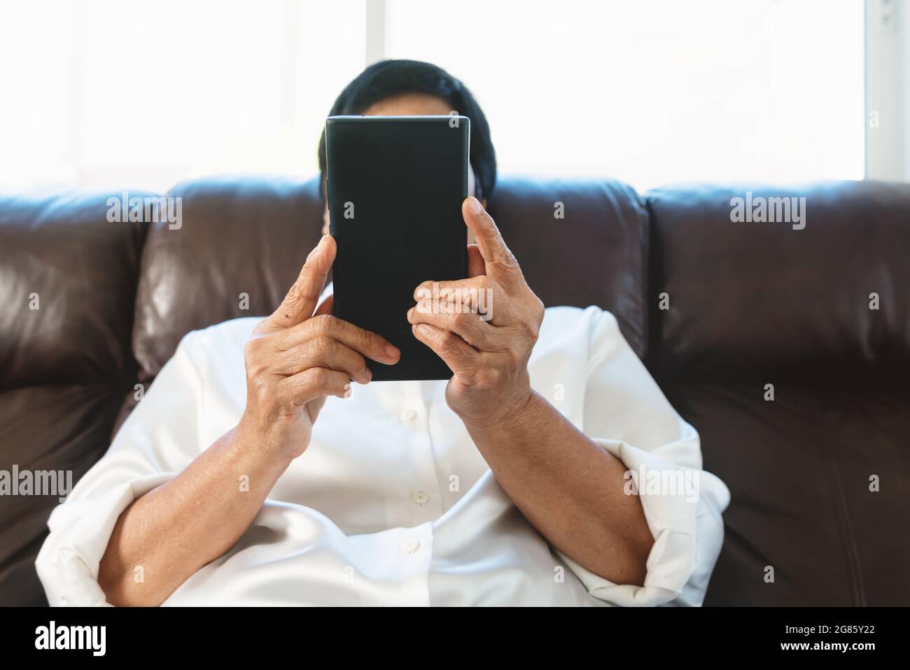 Senior woman using mobile phone while sitting on sofa at home Banque D'Images