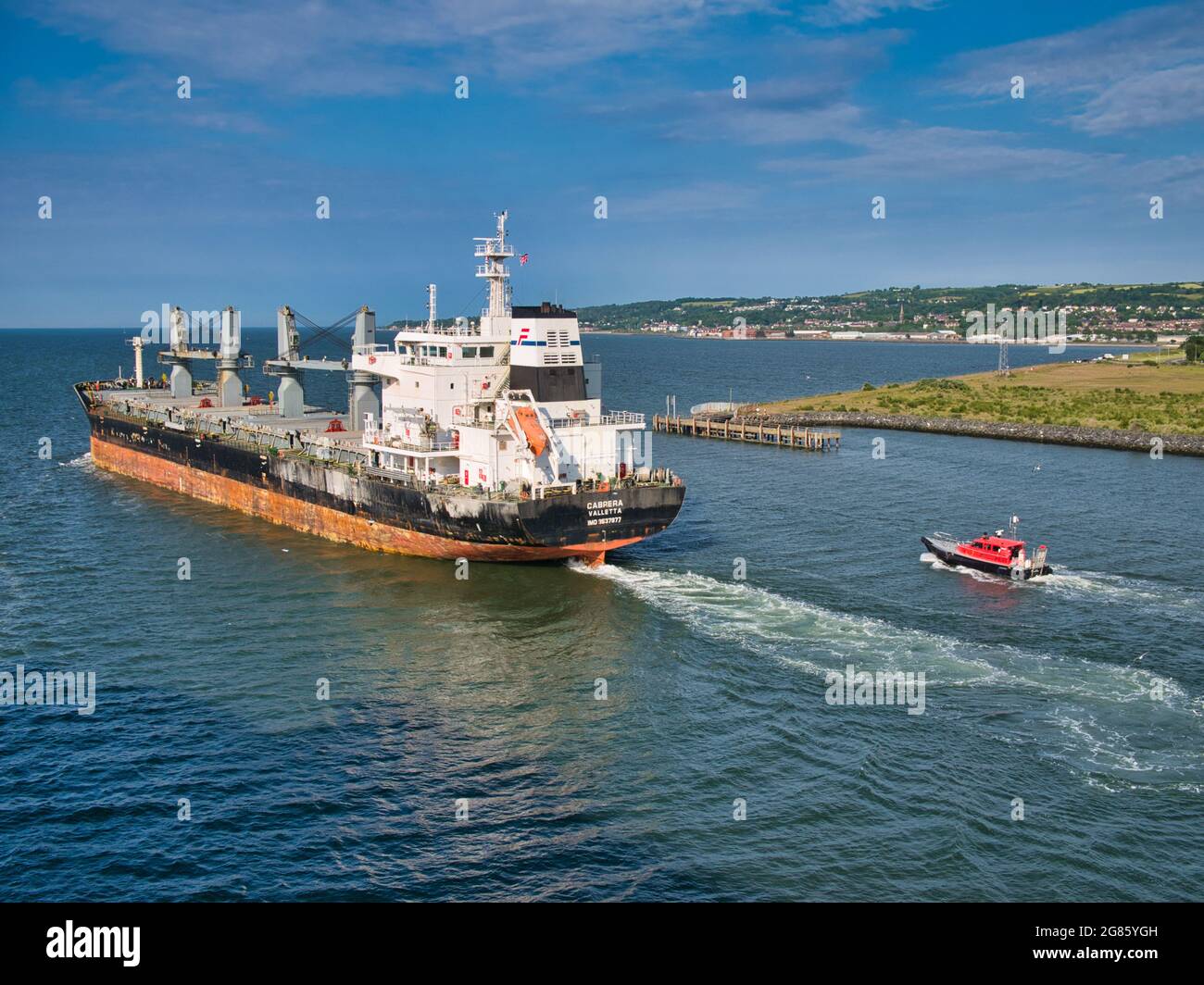 Le transporteur de vrac Cabrera quitte le port de Belfast en juin 2021 lors d'une soirée claire et ensoleillée en juin 2021. Le navire est escorté par le bateau à remorqueurs Masterman. Banque D'Images