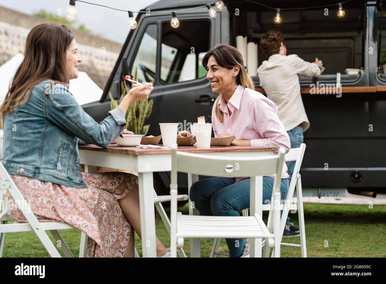Des femmes matures heureuses qui s'amusent à manger dans un camion de restauration de rue en plein air Banque D'Images