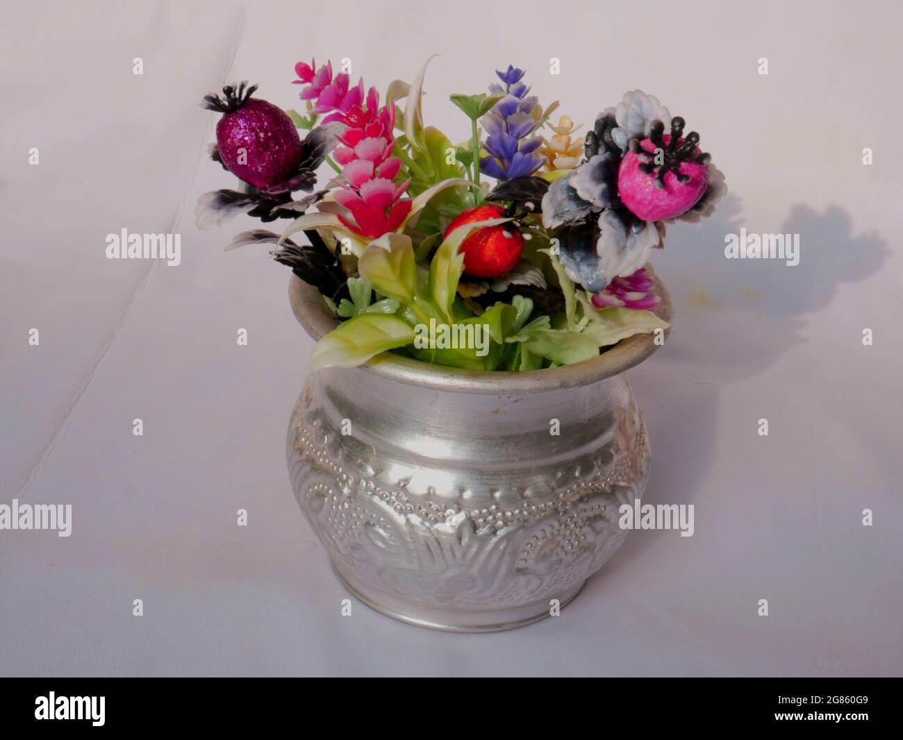Fleur artificielle présentée sur pot en métal argenté sur fond blanc, image d'objet nature. Banque D'Images