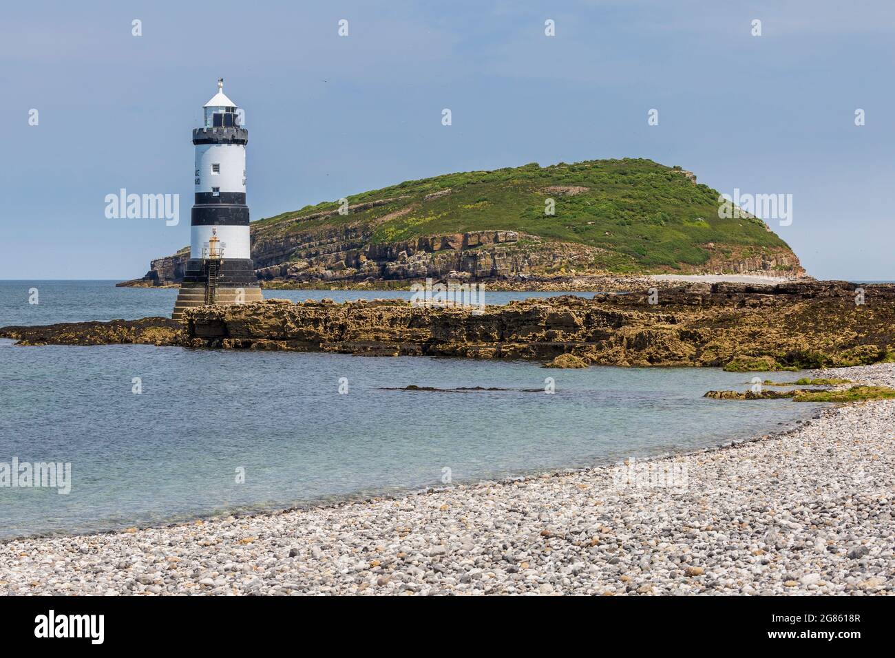 La plage de galets à Penmon point avec le phare et Puffin Island en arrière-plan, Anglesey, au nord du pays de Galles Banque D'Images