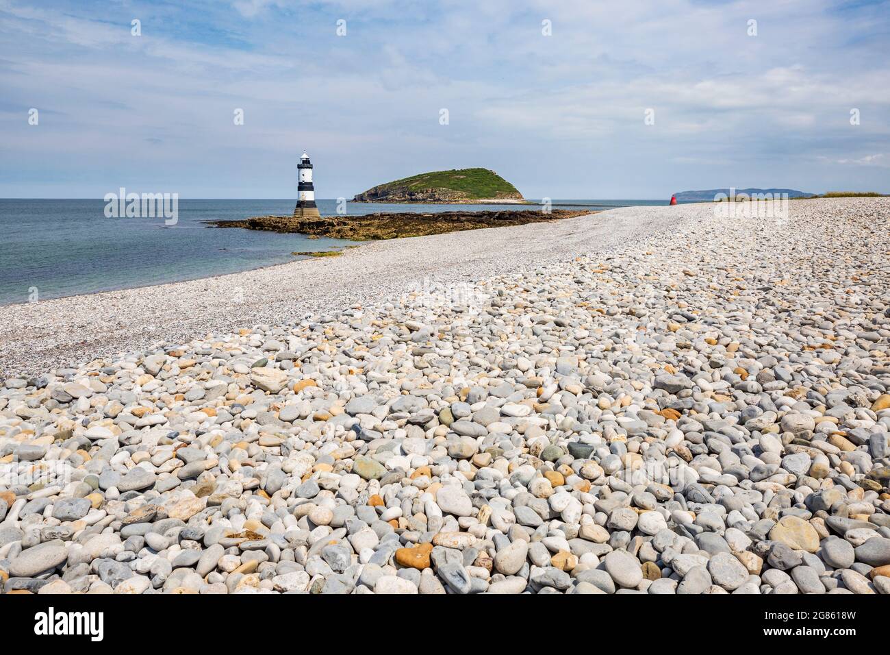 La plage de galets à Penmon point avec le phare et Puffin Island en arrière-plan, Anglesey, au nord du pays de Galles Banque D'Images