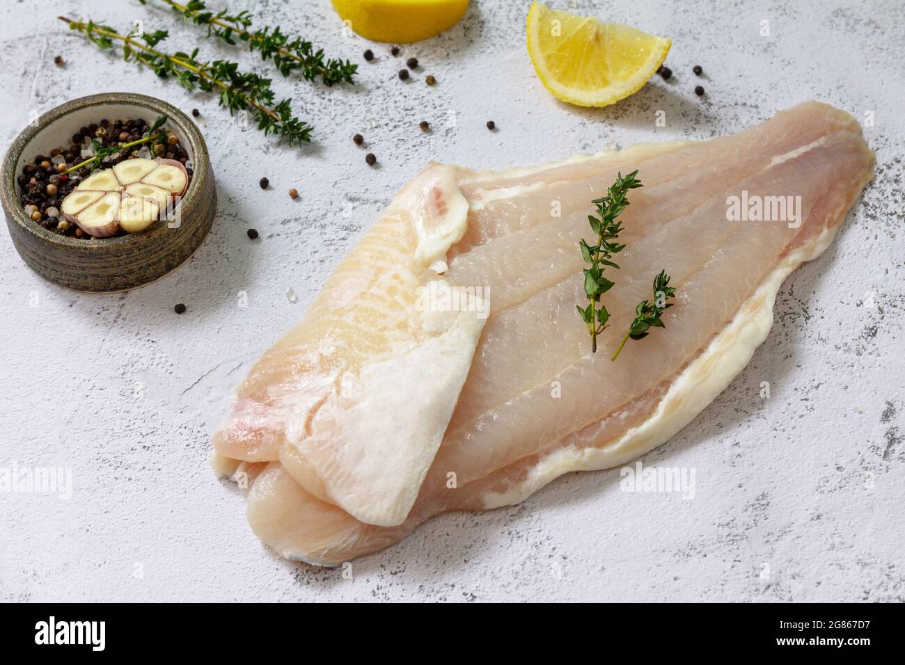 Fruits de mer, filet de poisson blanc cru pour la cuisine. Filet de Pangasius frais avec épices, citron et thym sur fond de pierre. Banque D'Images