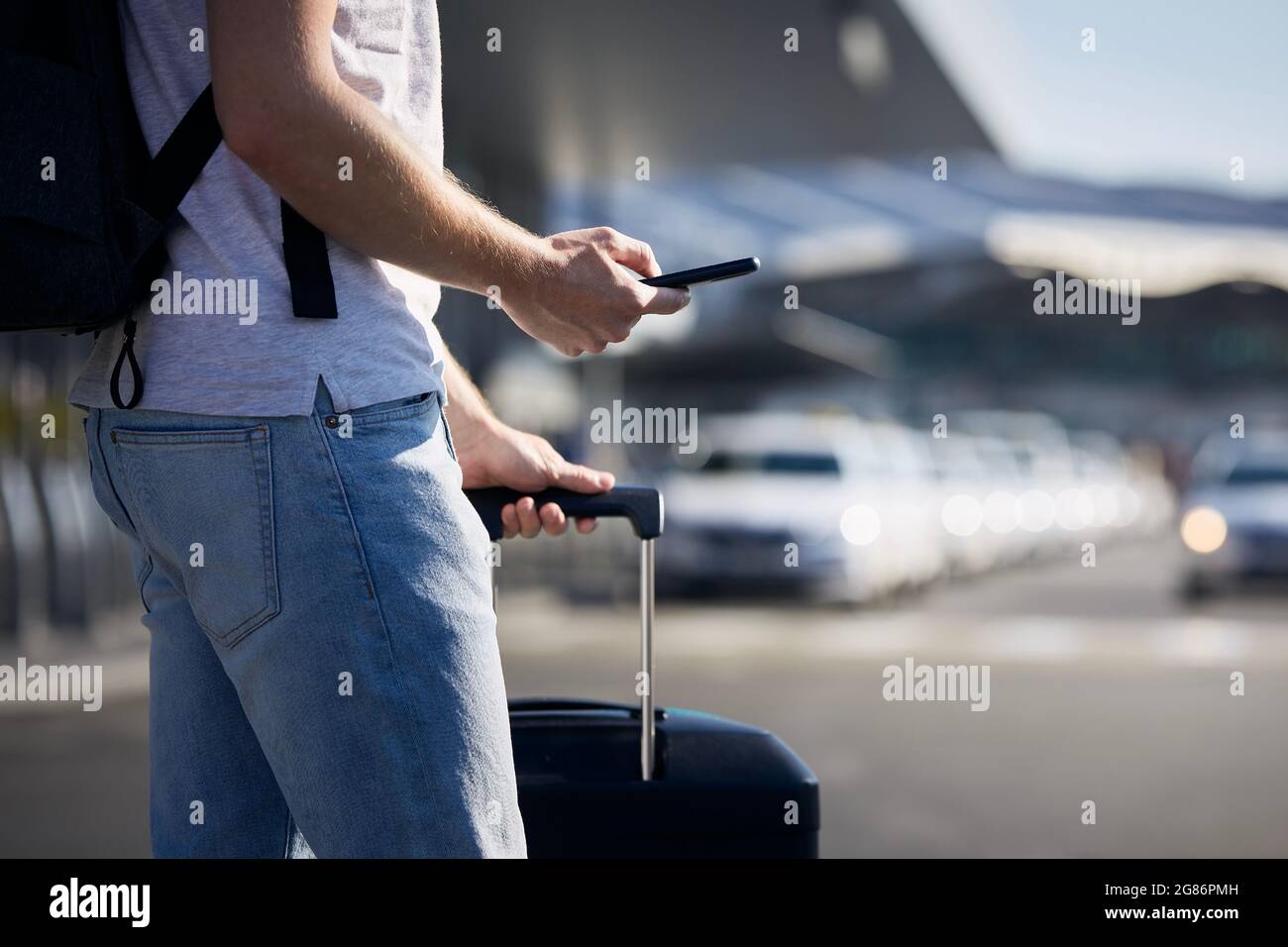 Homme tenant un smartphone et utilisant une application mobile contre une rangée de voitures de taxi. Thèmes technologie moderne, partage de voitures et voyages. Banque D'Images