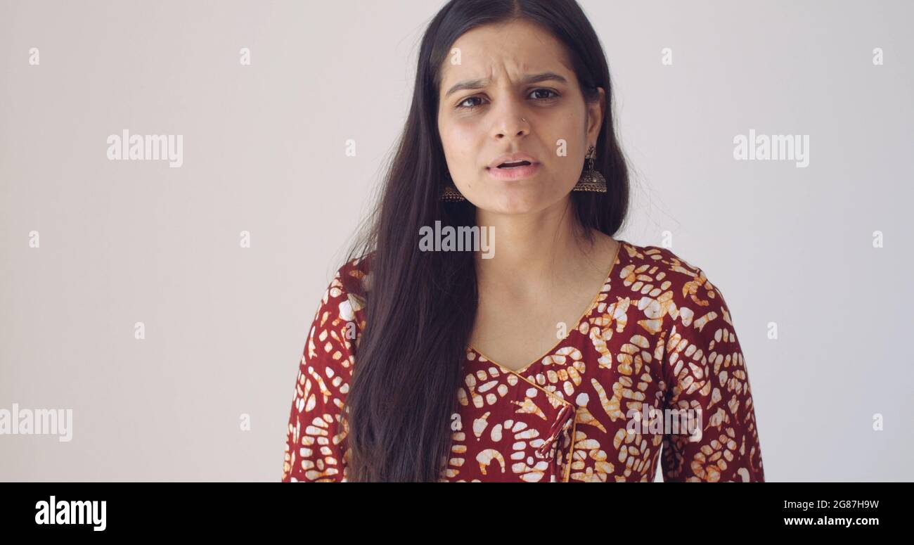 Jolie femme indienne avec une expression de visage frowned sur un fond blanc Banque D'Images