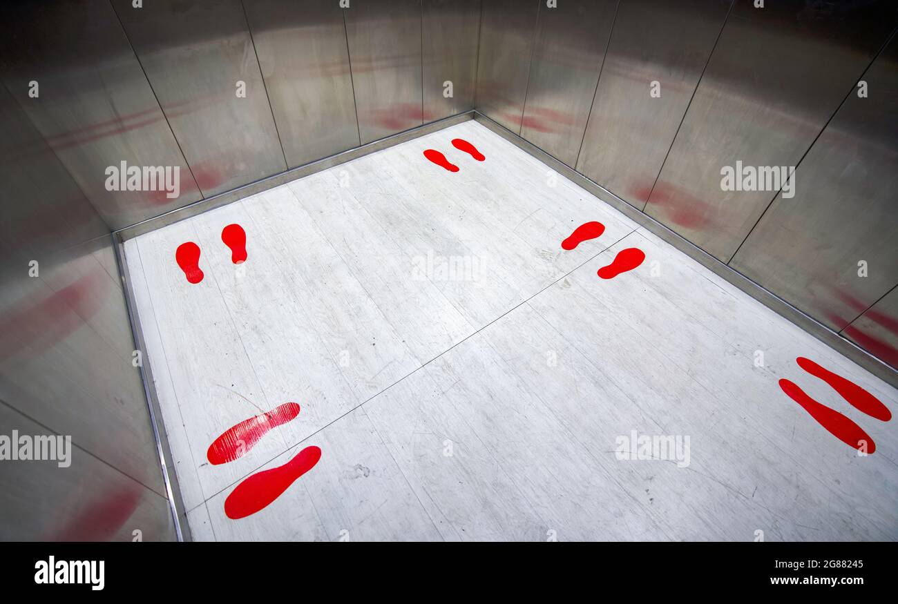 Le symbole d'empreinte rouge à l'intérieur de l'ascenseur indique la position debout et la distance de chaque personne. Distanciation sociale pour réduire la propagation de la dise infectieuse Banque D'Images