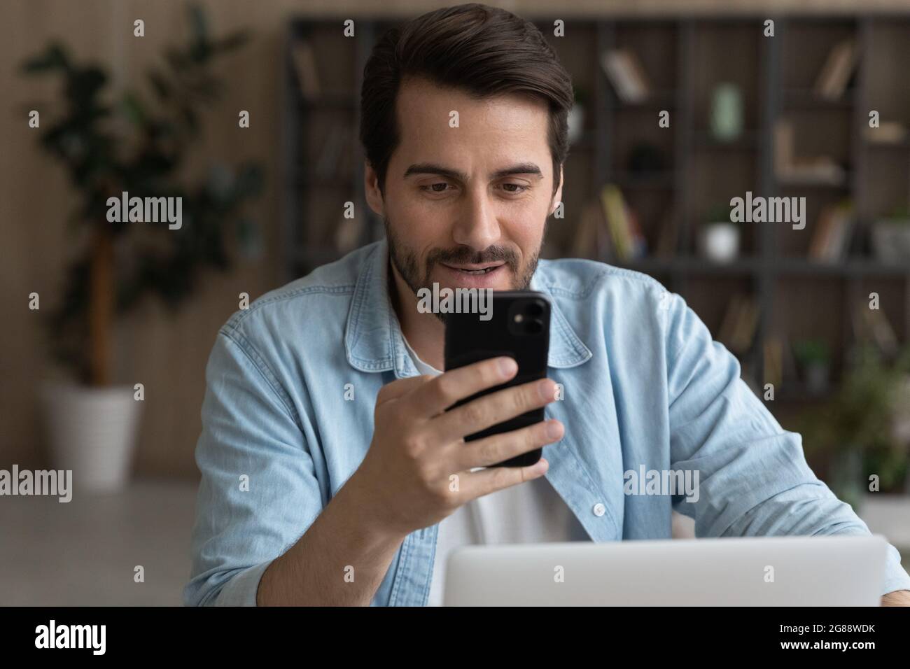 Jeune homme d'affaires souriant utilisant un smartphone au bureau. Banque D'Images