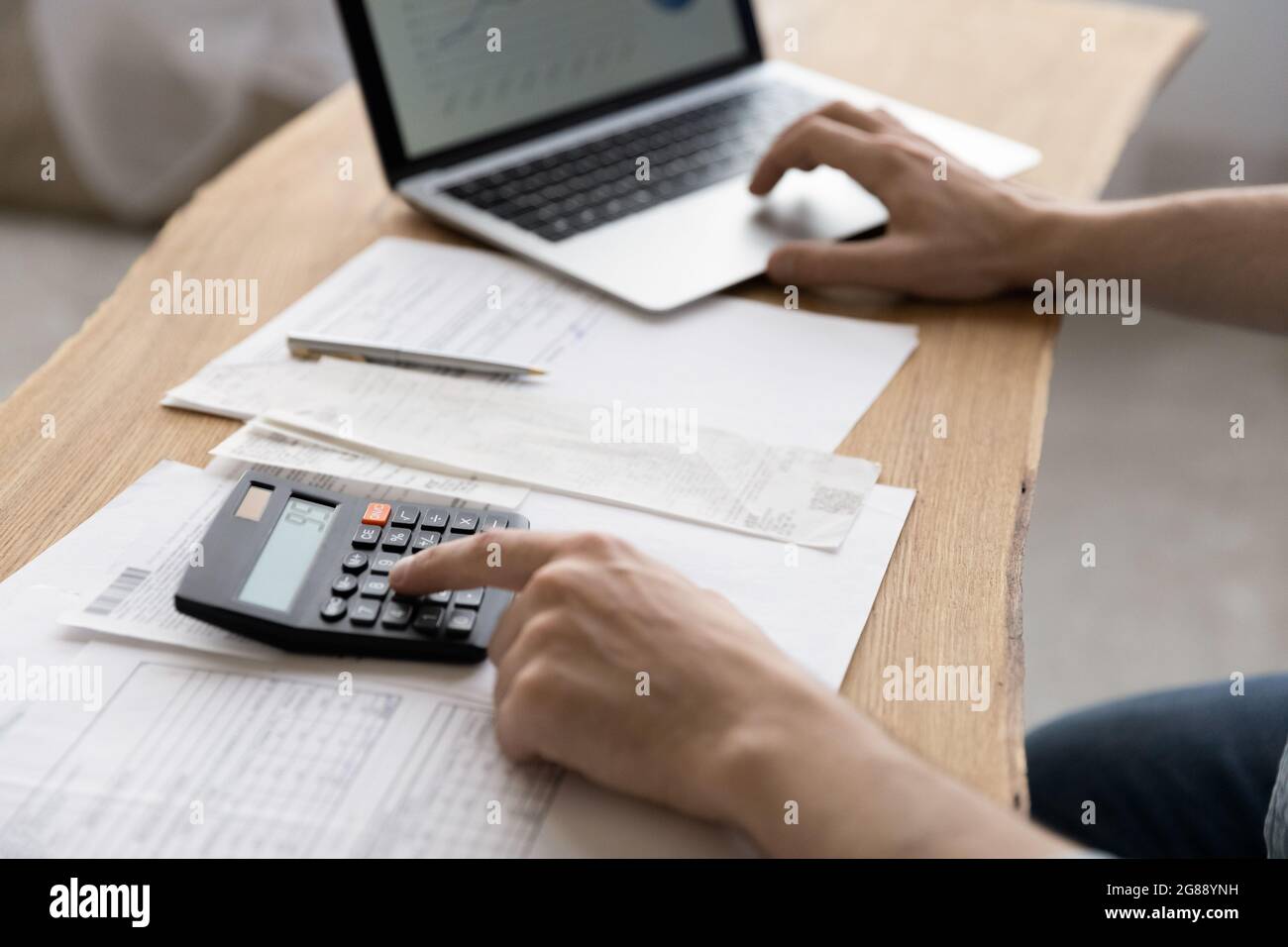 Gros plan jeune homme en utilisant la calculatrice résumant les factures de services publics domestiques. Banque D'Images